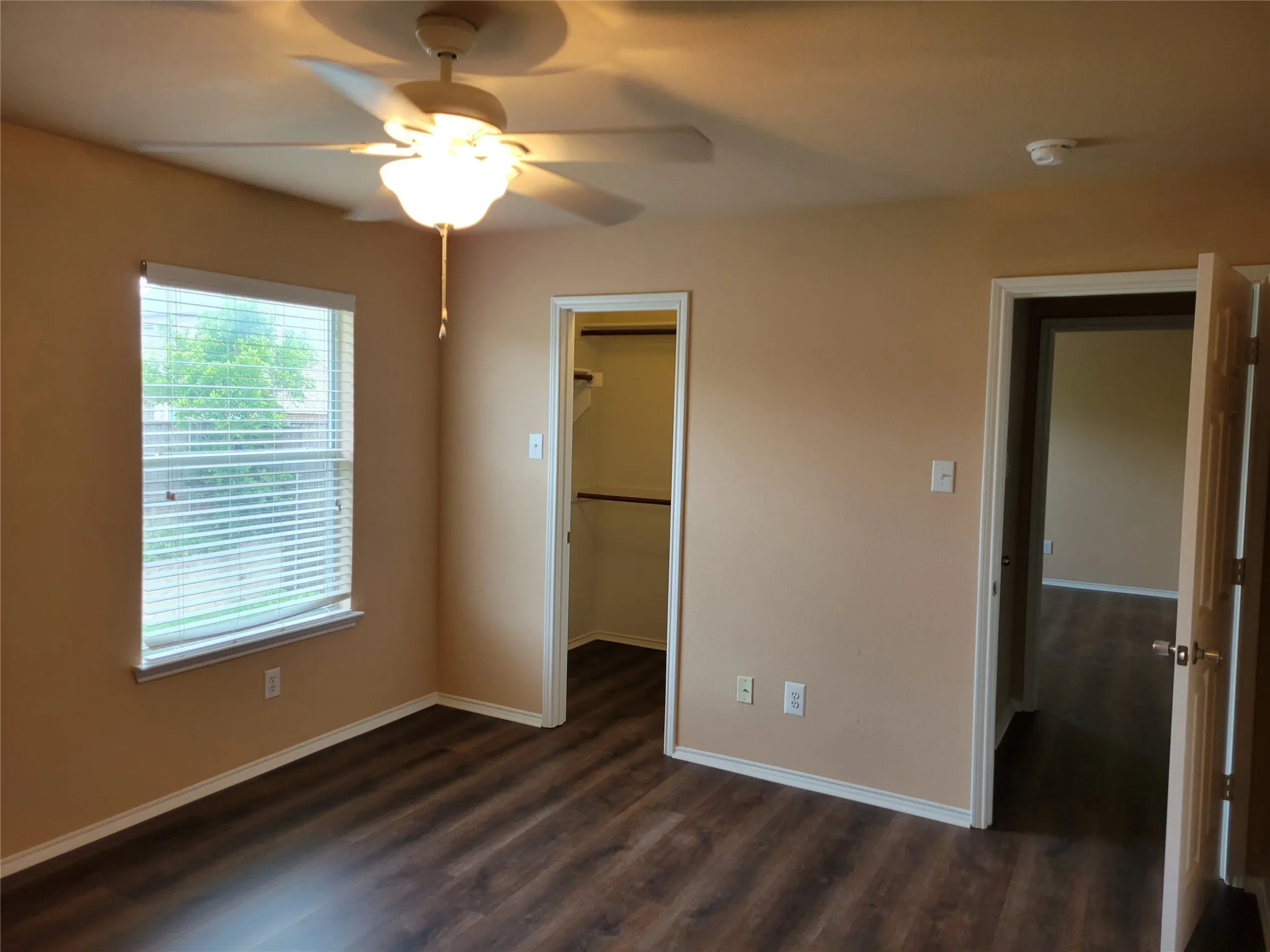 One of 3 bedrooms upstairs featuring laminate flooring, ceiling fan, walk-in closet, and plenty of natural light