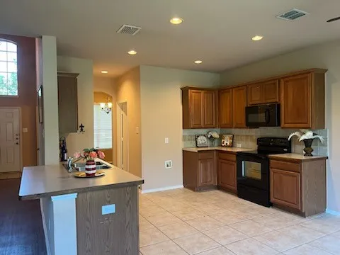Kitchen featuring black appliances, tasteful backsplash, light tile floors, and kitchen peninsula