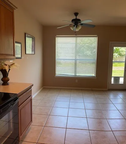 Unfurnished breakfast area with ceiling fan and light tile flooring