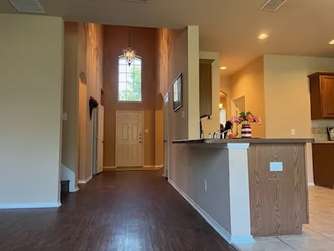 Foyer with dark laminate floors, an inviting chandelier, and a high ceiling