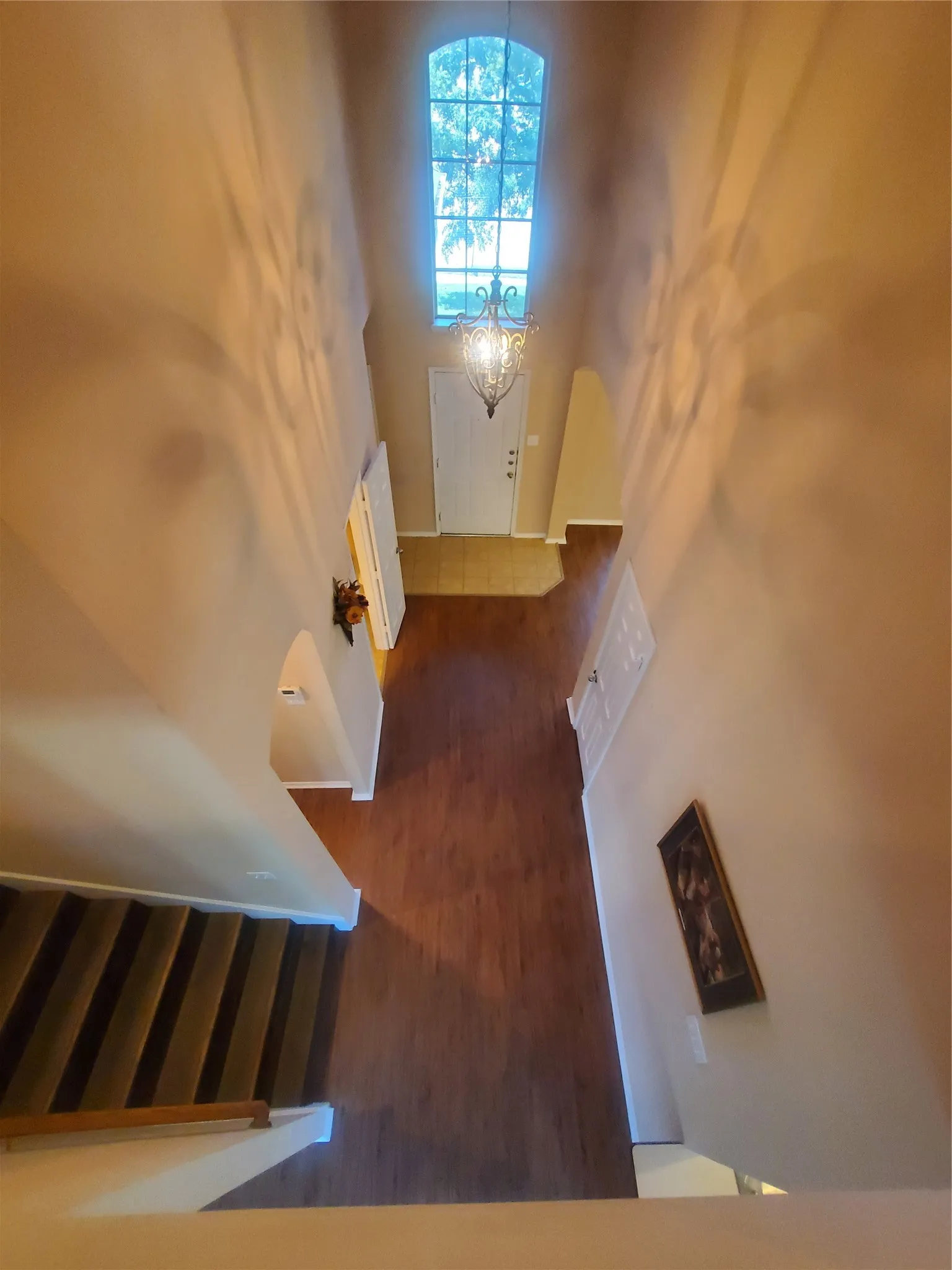 Foyer featuring laminate floors, a notable chandelier, and a high ceiling