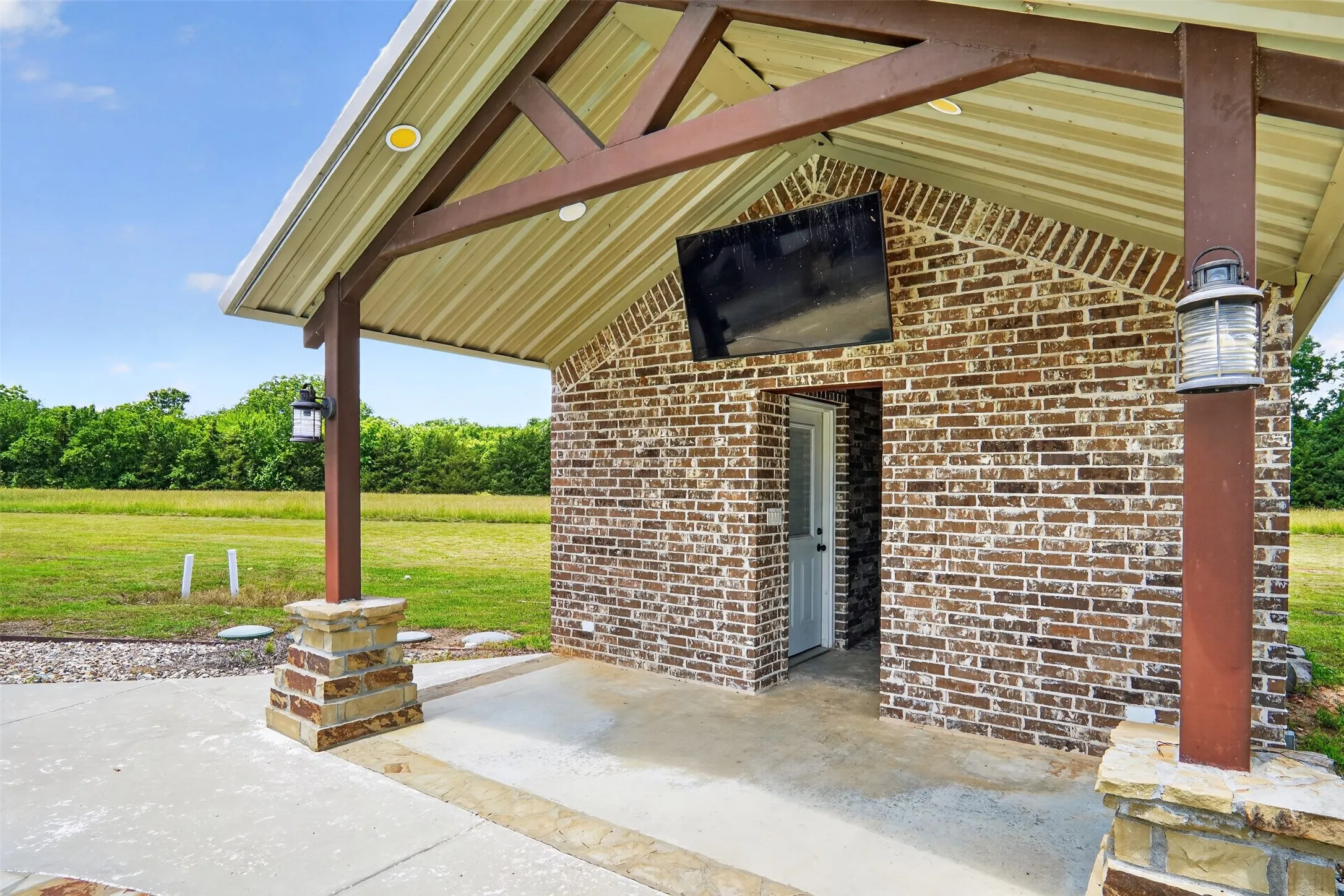 40 x 60 building with covered patio featuring a brick accent wall, concrete flooring, and a corrugated metal roof