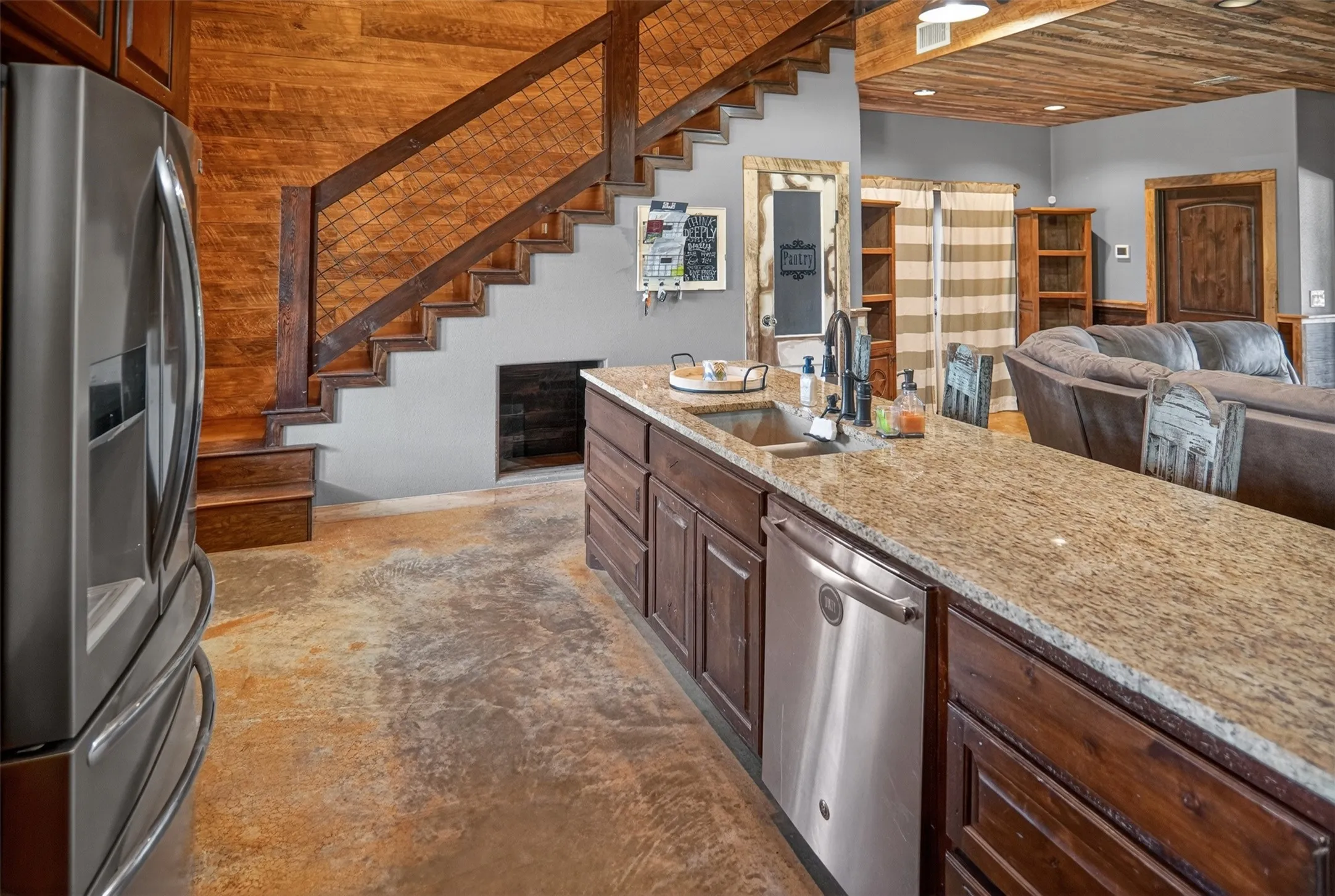 Kitchen island featuring a granite countertop, stainless steel sink, and integrated dishwasher