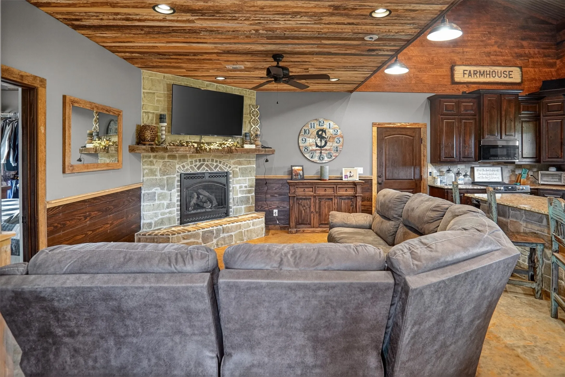 Living area featuring a stone gas log, fireplace with hearth, wood-finish wainscoting, and a wood-plank ceiling