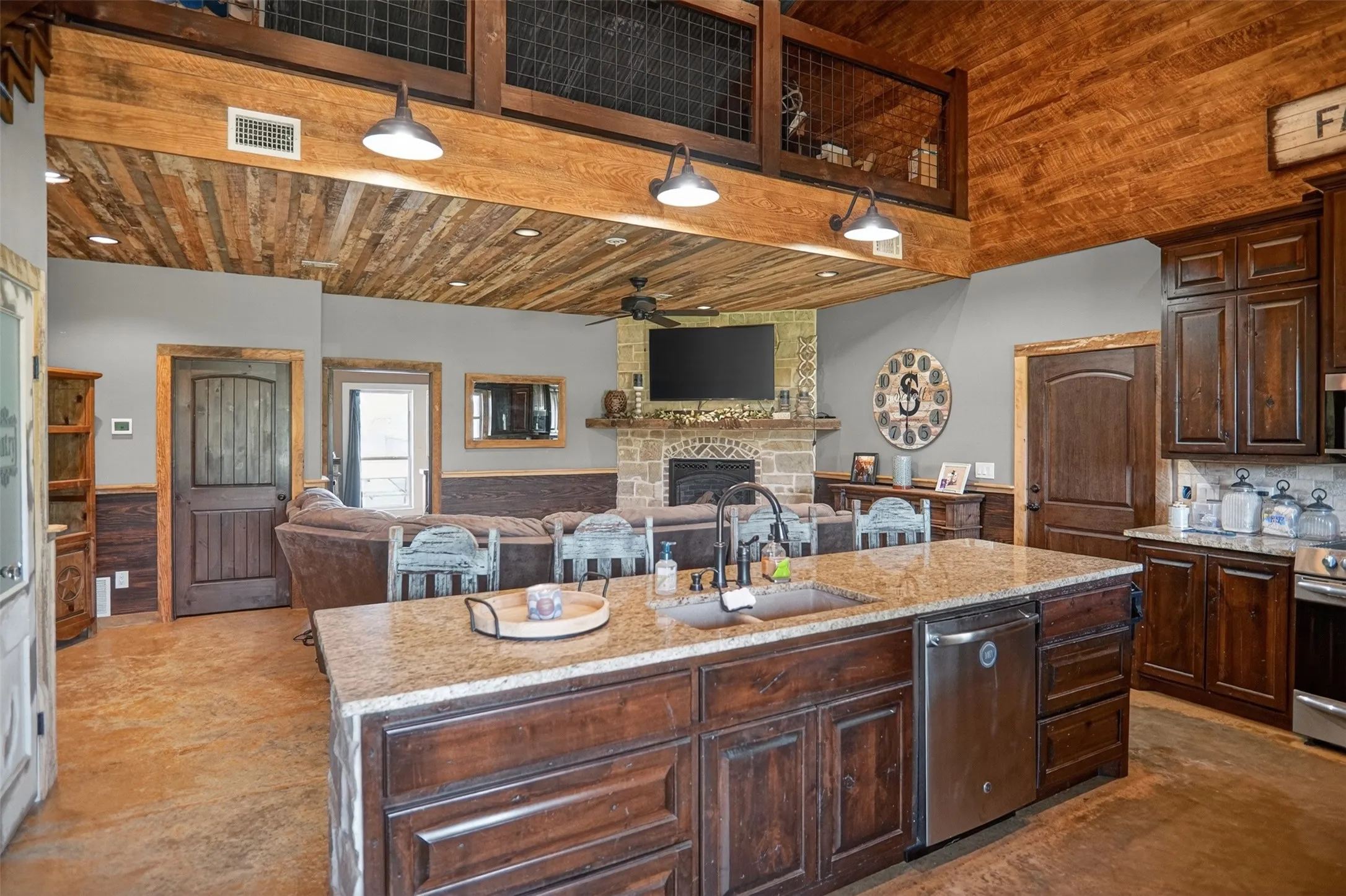 Open-concept living space featuring a central kitchen island with a granite countertop, integrated sink, and stainless steel dishwasher