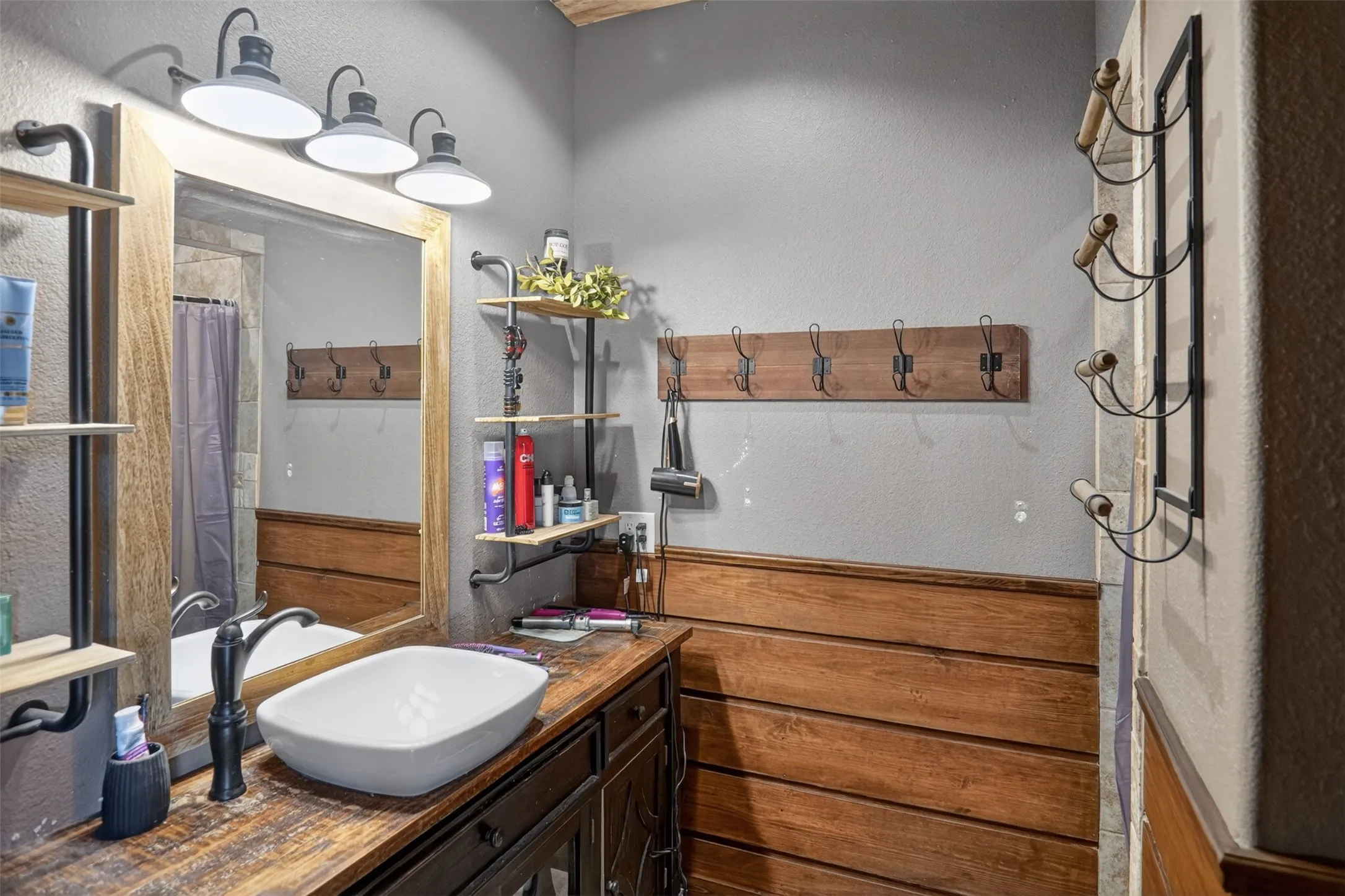 1st floor bathroom vanity featuring a vessel sink, wood-finish countertop, and dark cabinetry