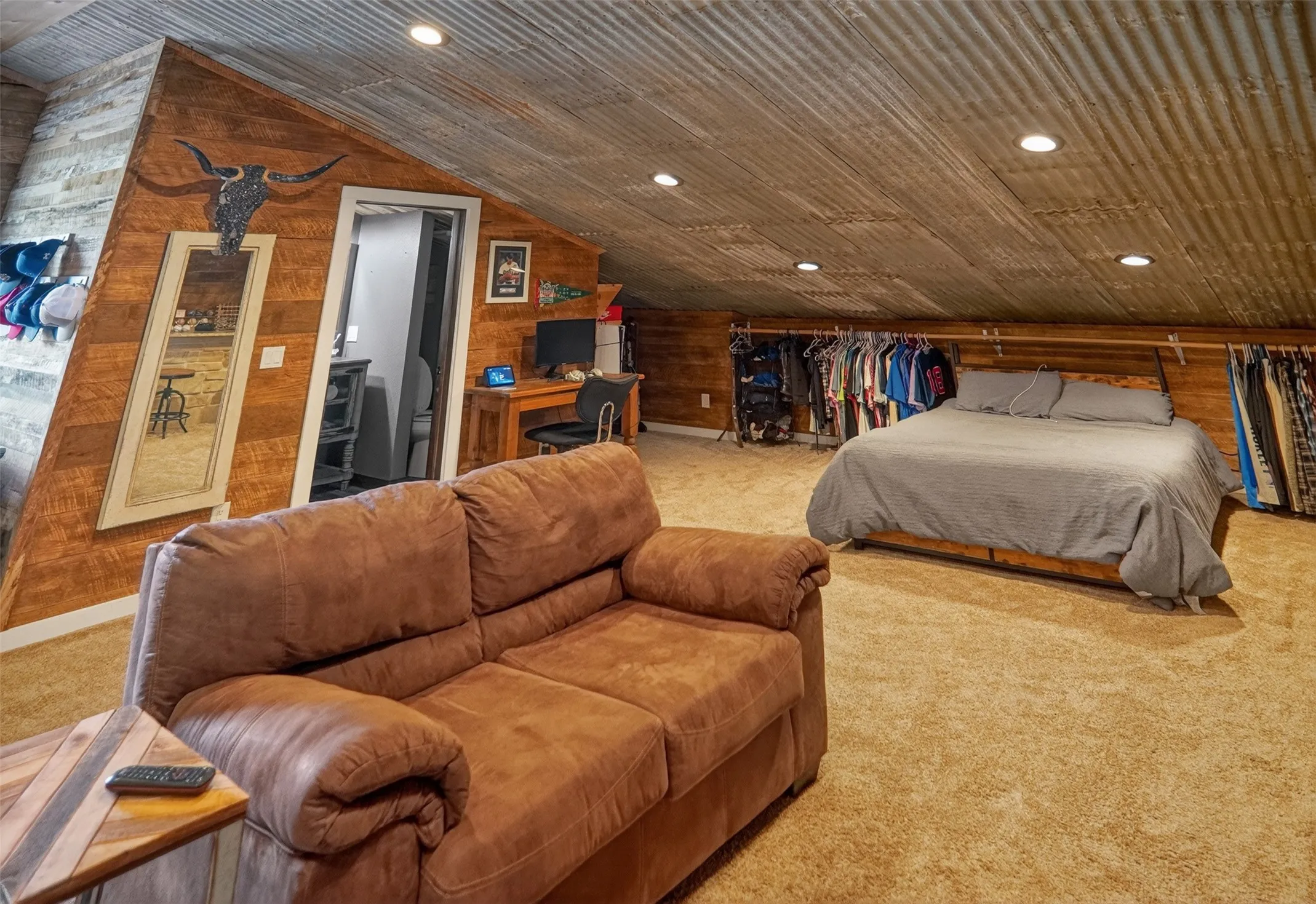 Spacious 2nd bedroom featuring corrugated metal ceiling, recessed lighting, wood-paneled accent wall, and carpet flooring
