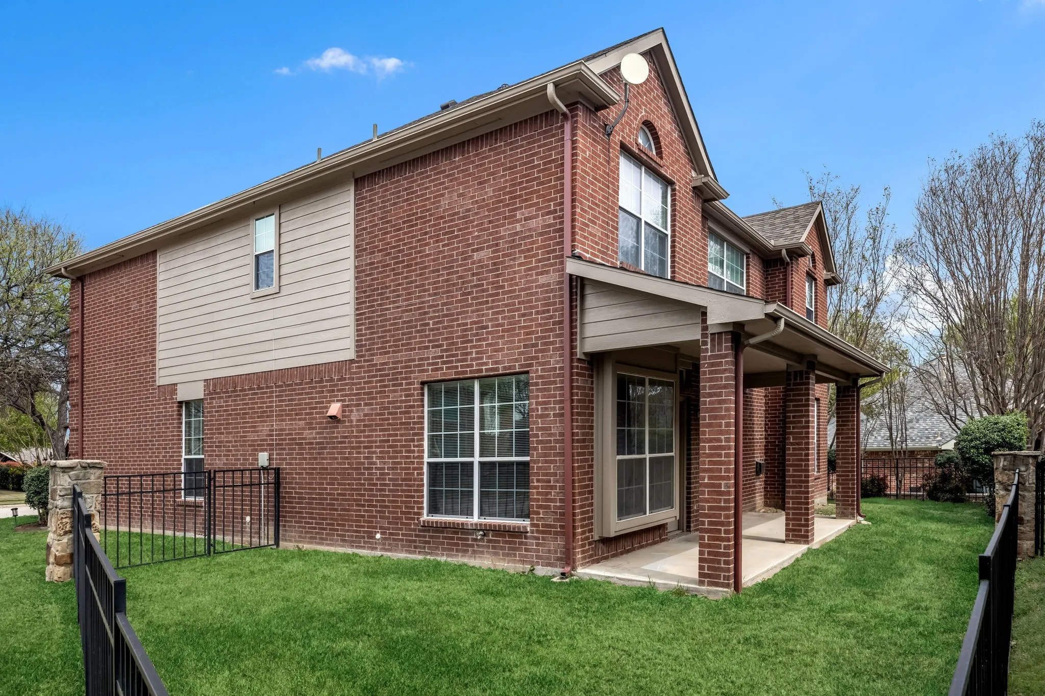 View of side of home featuring a fenced backyard, brick siding, and a patio