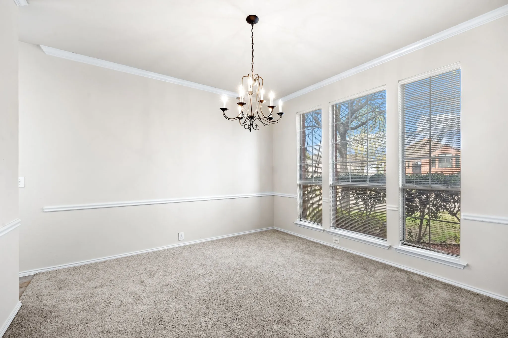 Spare room featuring carpet floors, a chandelier, and crown molding