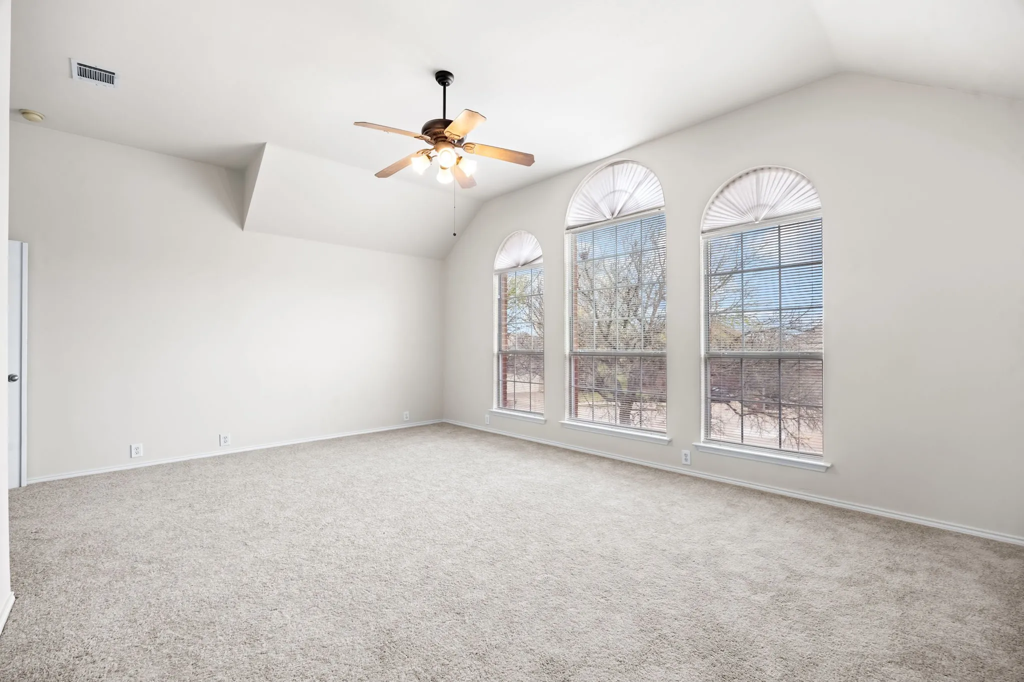 Spare room featuring vaulted ceiling, carpet floors, and a ceiling fan