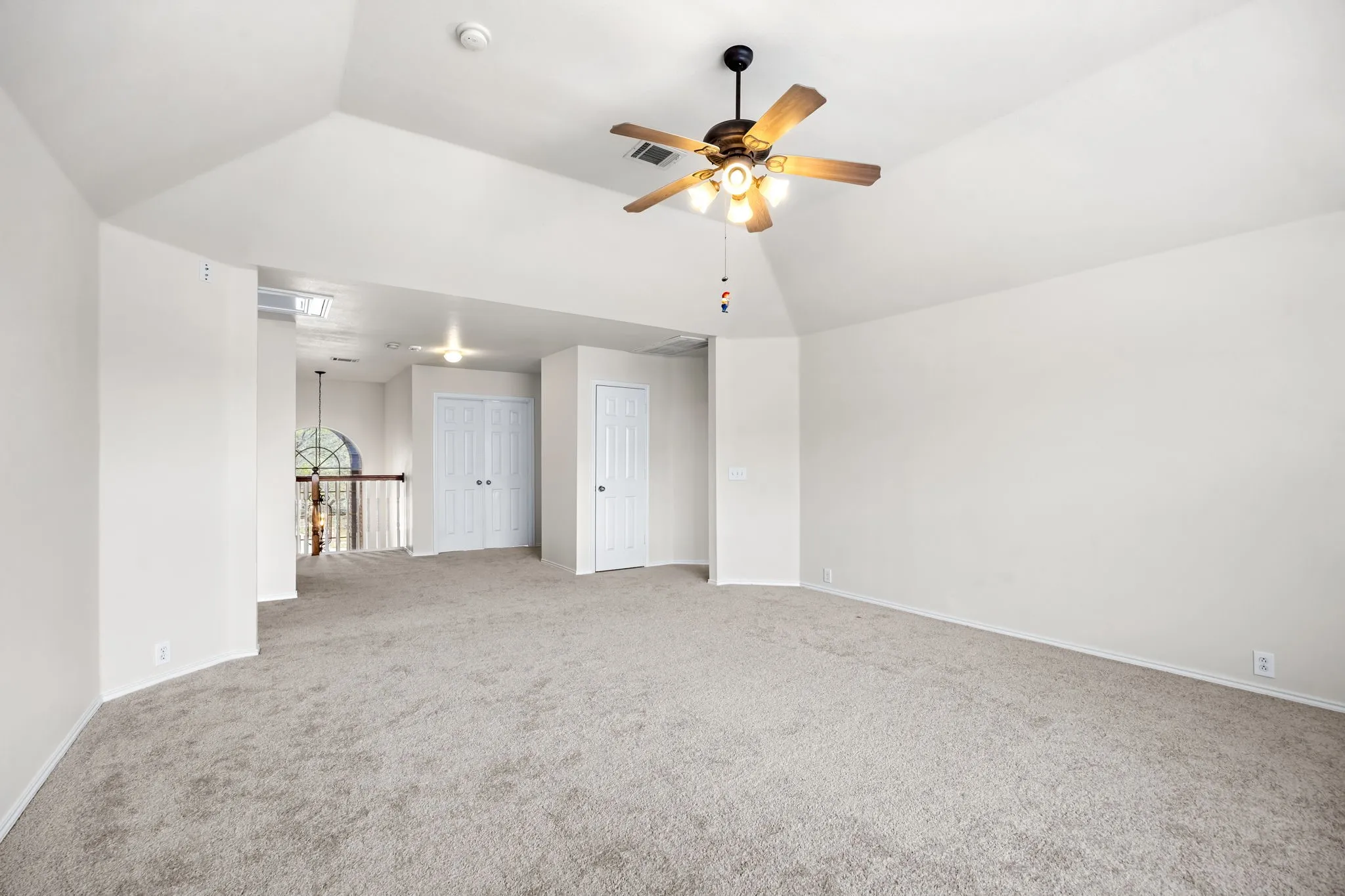 Carpeted spare room featuring vaulted ceiling and ceiling fan