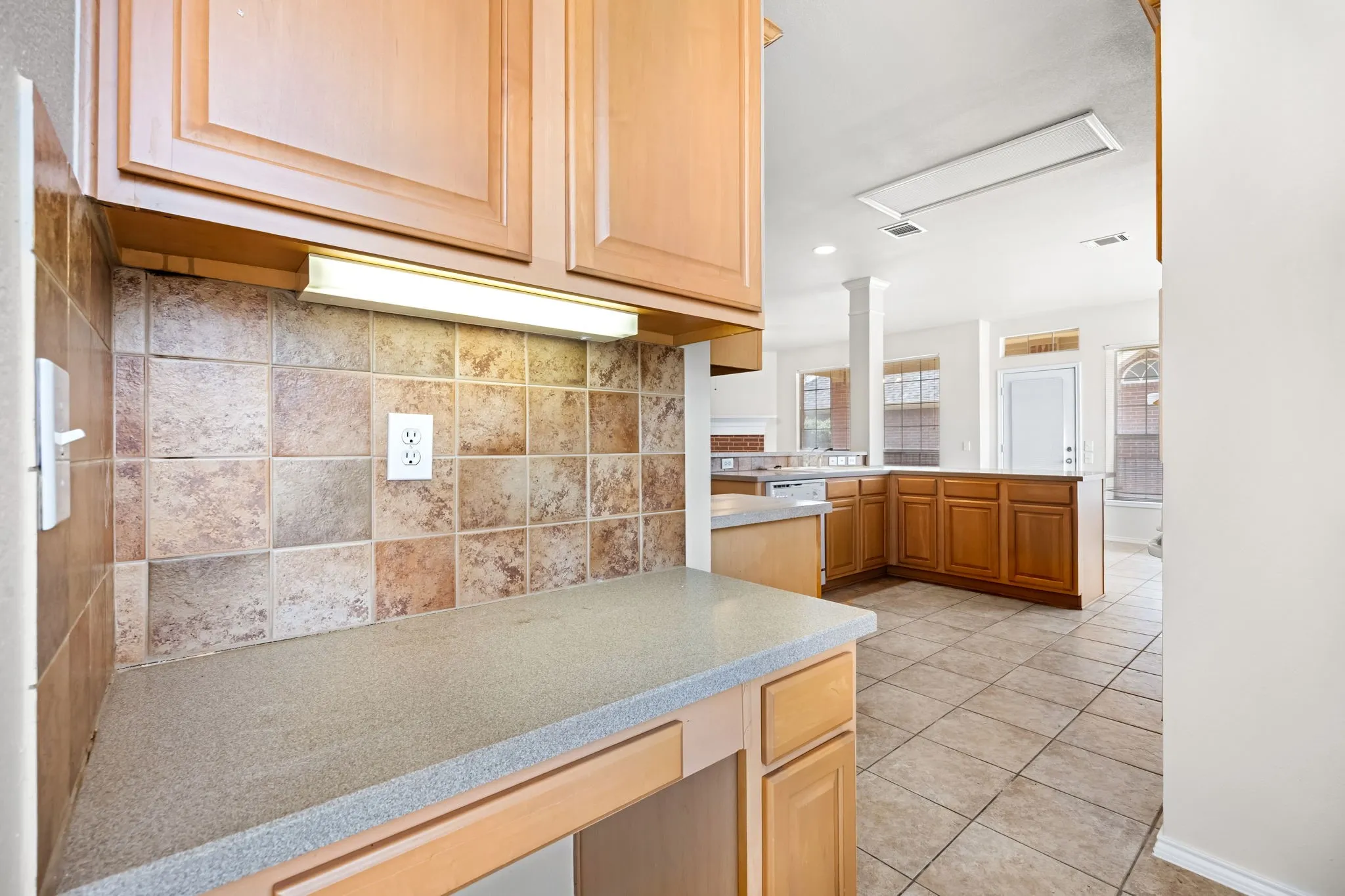 Kitchen featuring a peninsula, decorative backsplash, light tile patterned floors, recessed lighting, and light wood finish cabinets
