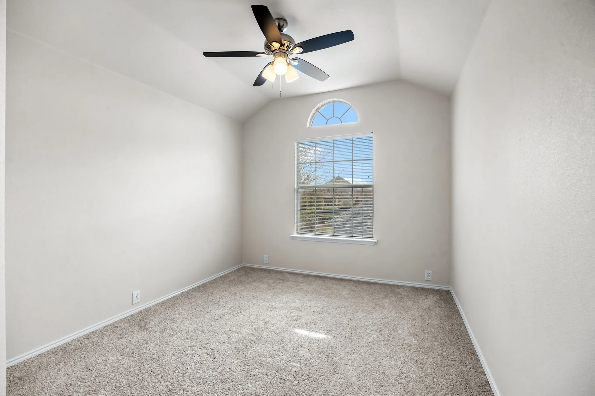 Carpeted spare room featuring a ceiling fan and baseboards