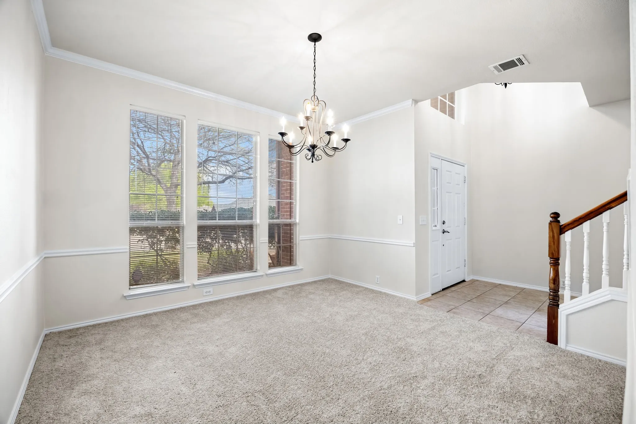 Unfurnished dining area with light carpet, hanging lights, and ornamental molding