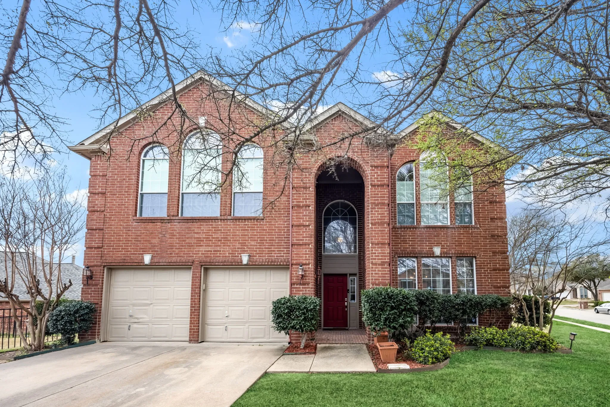 Traditional-style home with brick siding, driveway, an attached garage, and a front yard