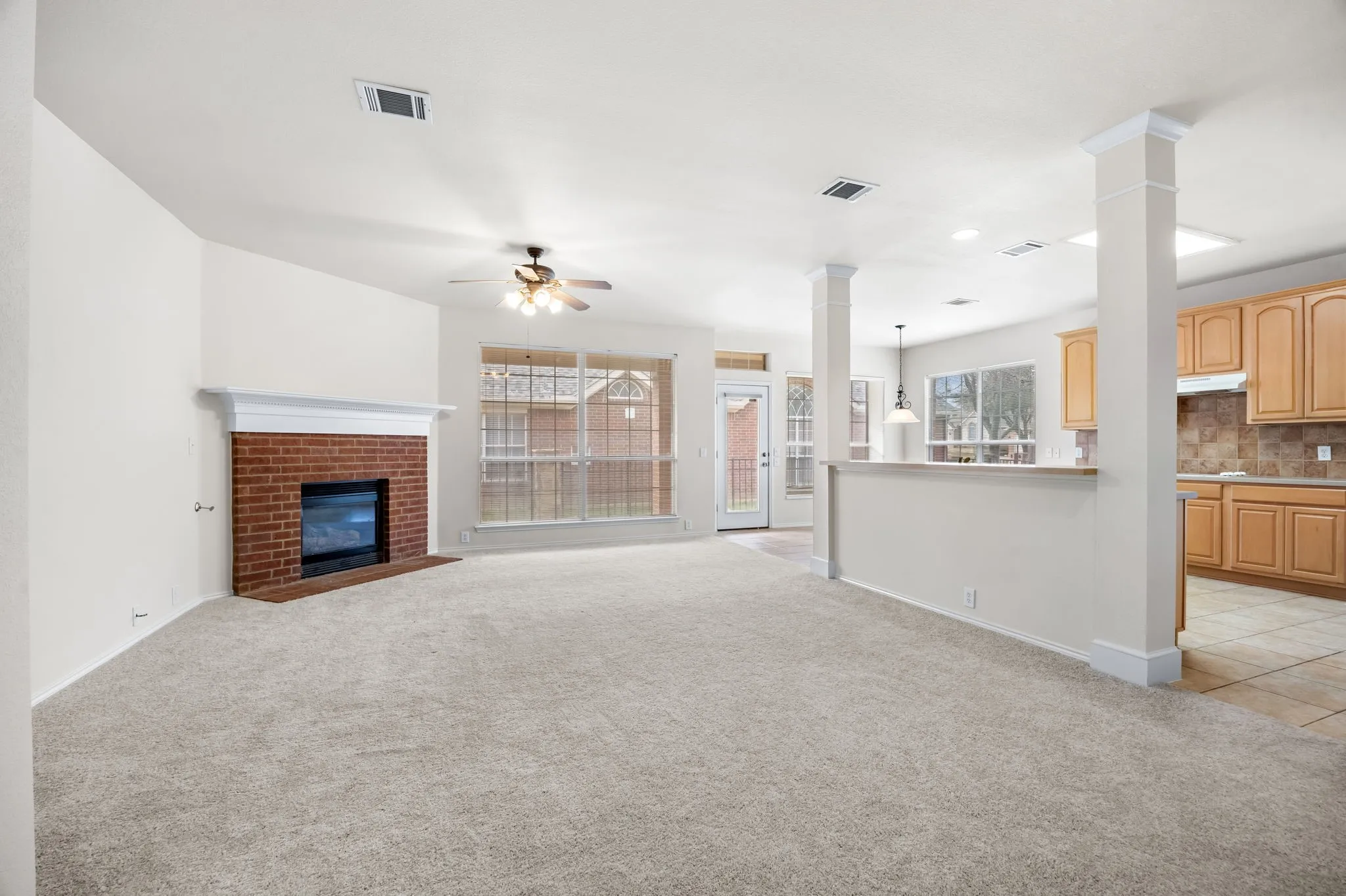 Unfurnished living room with light carpet, a fireplace, and ceiling fan
