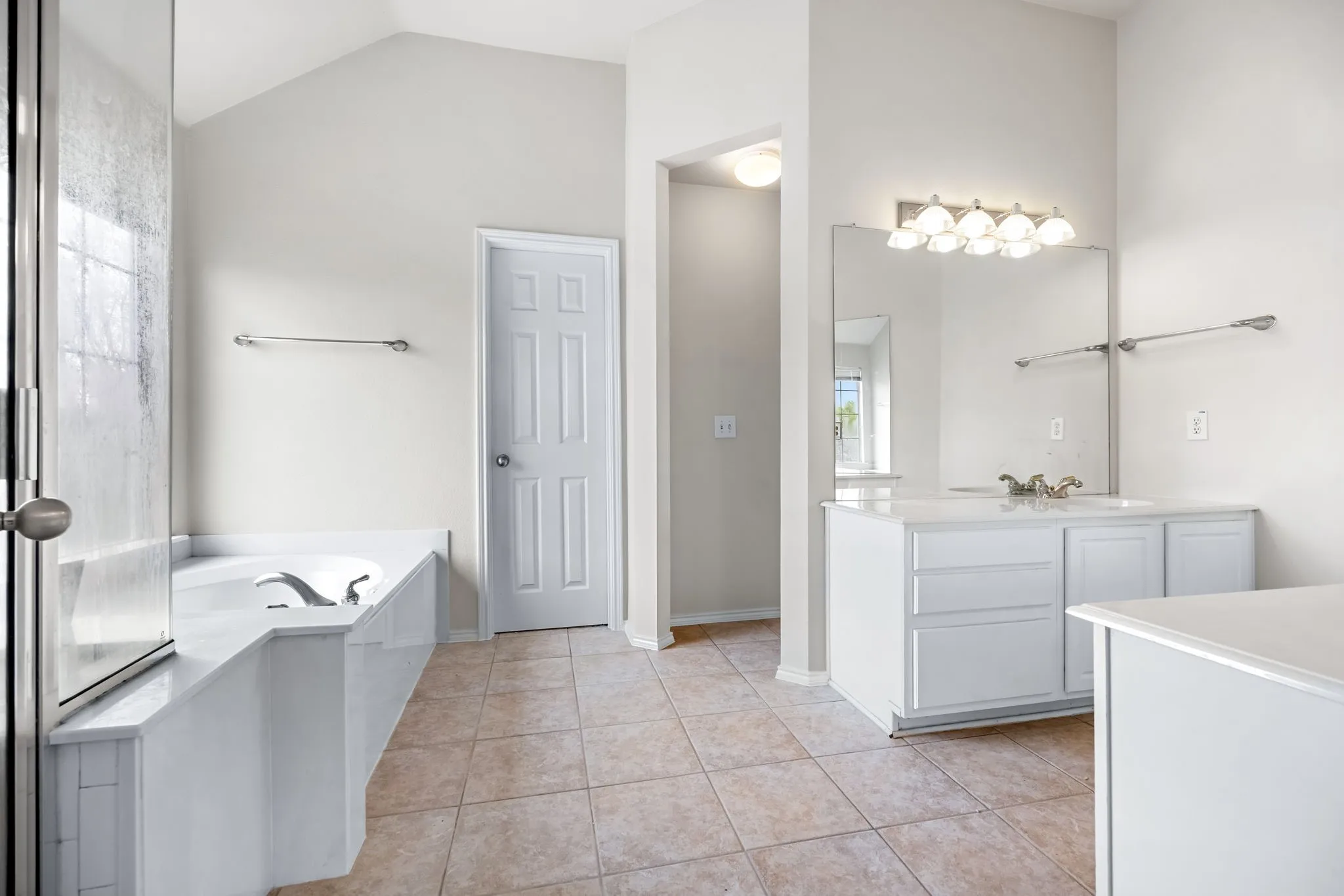 Bathroom with vanity, a garden tub, light tile patterned floors, and vaulted ceiling