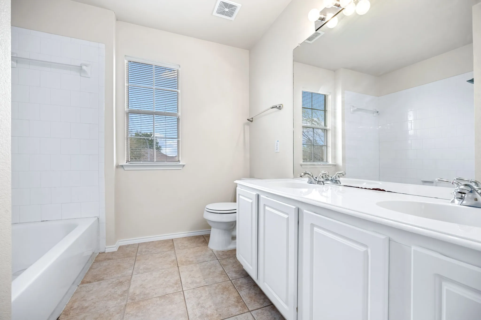 Bathroom with double vanity, healthy amount of natural light, light tile patterned flooring, and shower / bath combination