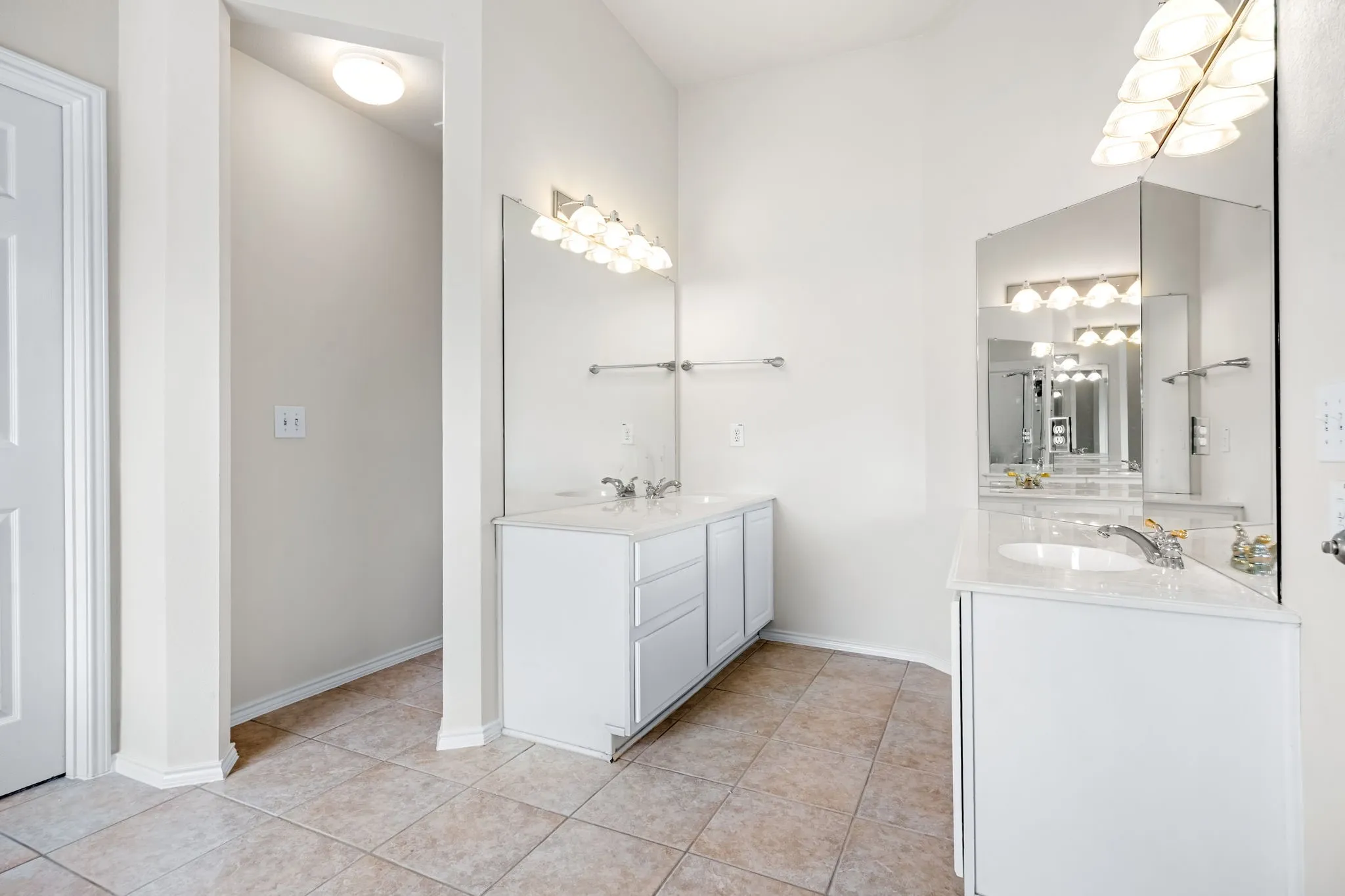 Bathroom with two vanities, light tile patterned flooring, and hanging lights