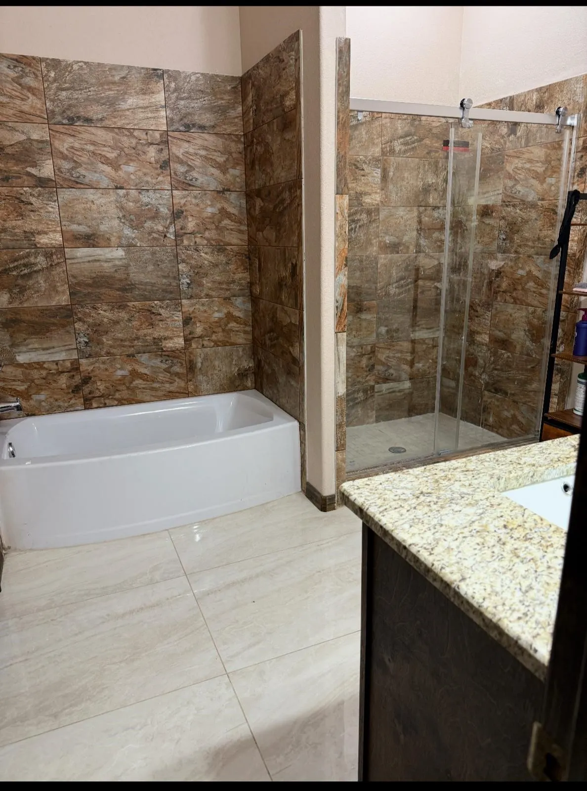 Bathroom featuring a white soaking tub, an enclosed shower with a sliding glass door, and a vanity with a light-toned countertop