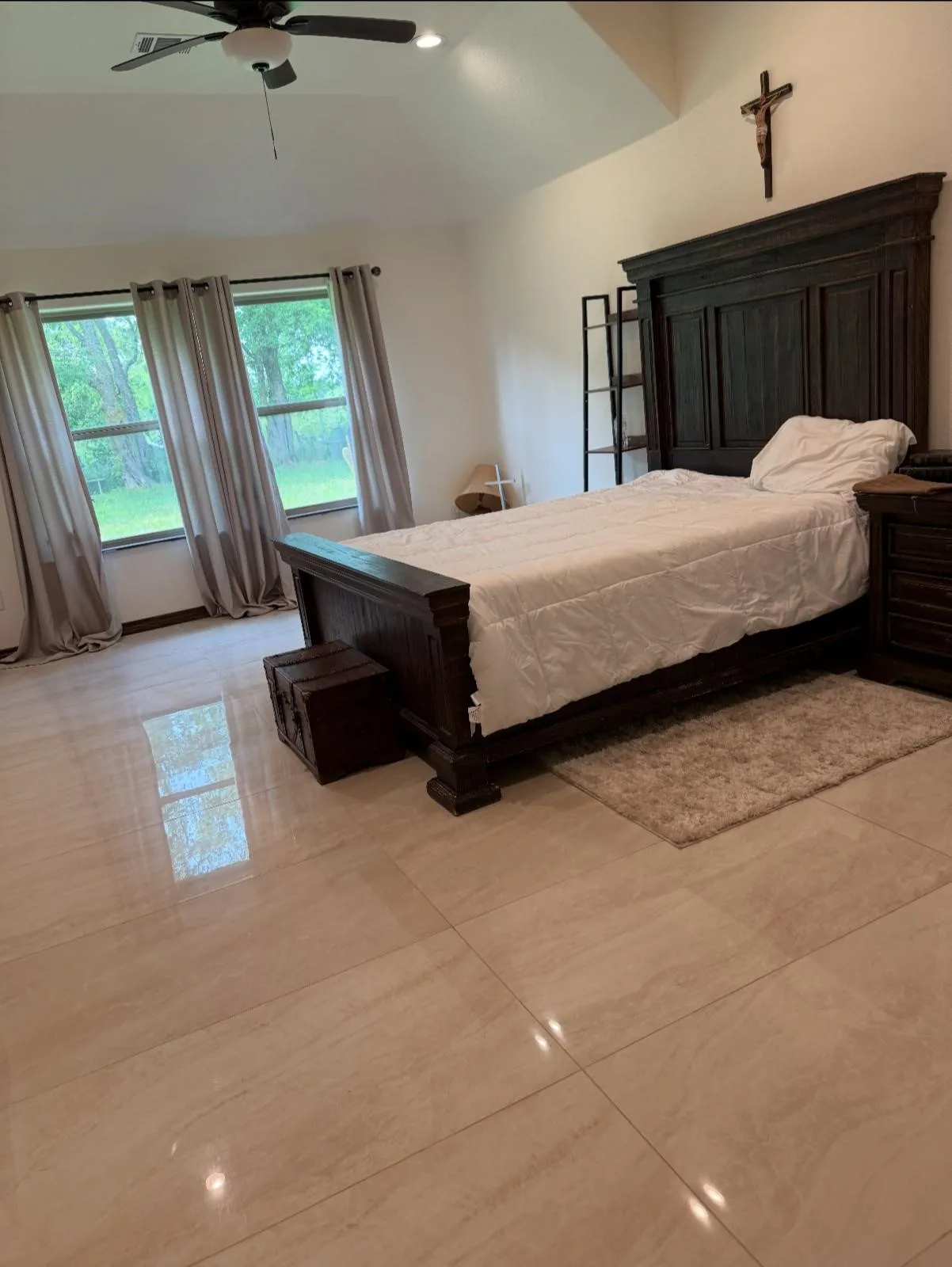 Room featuring vaulted ceilings, light-toned large format tile flooring, and multiple windows with exterior views