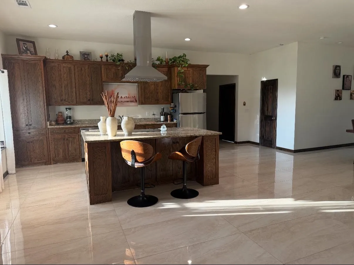 Spacious kitchen featuring extensive wood cabinetry, granite countertops, and a central island with bar seating