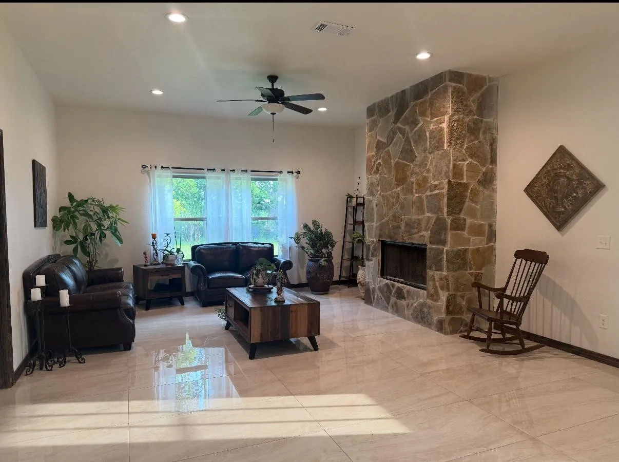 Living area featuring a stone-clad fireplace and light-toned tile flooring