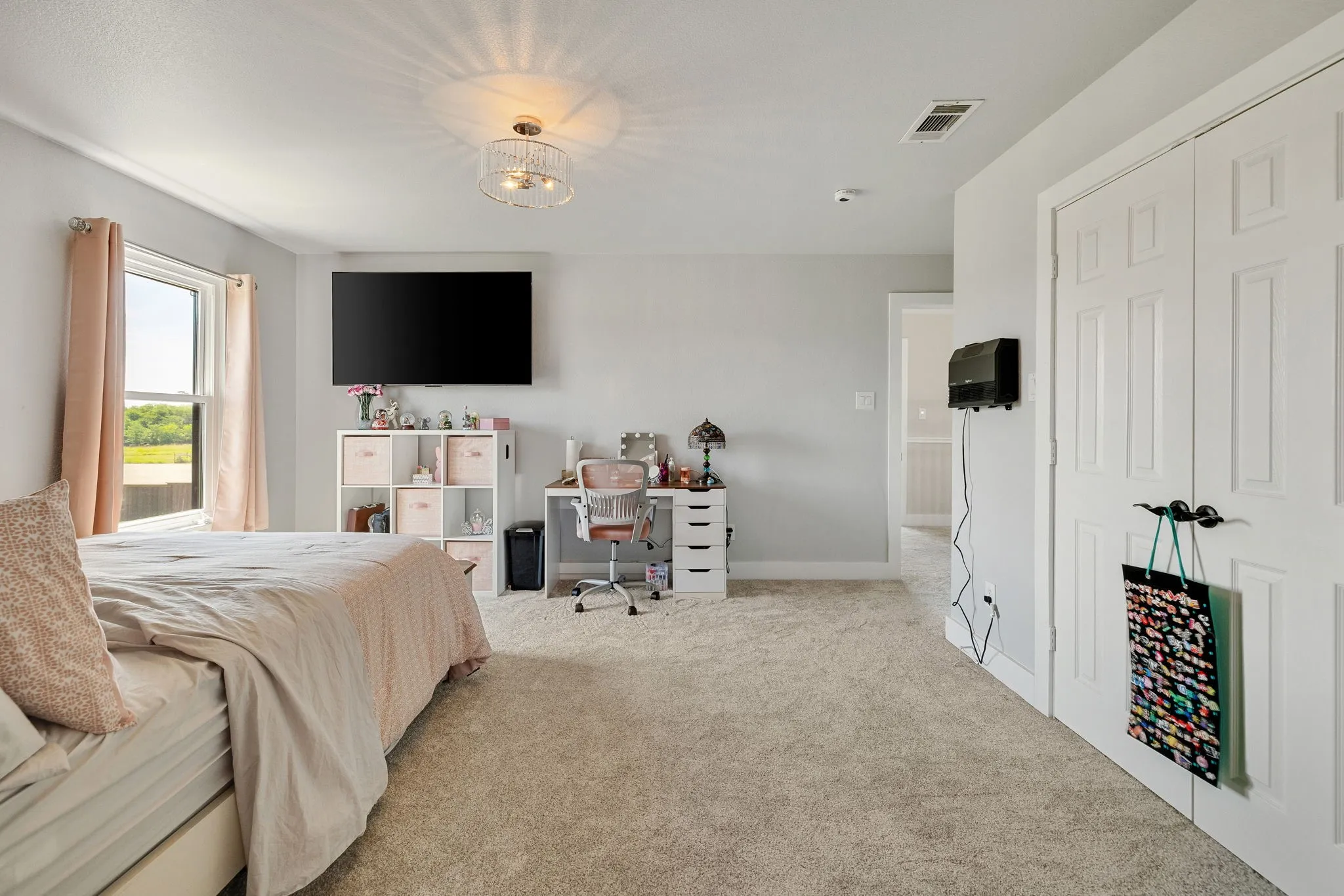 Plush carpeting, a large window, and a modern ceiling light fixture define this room