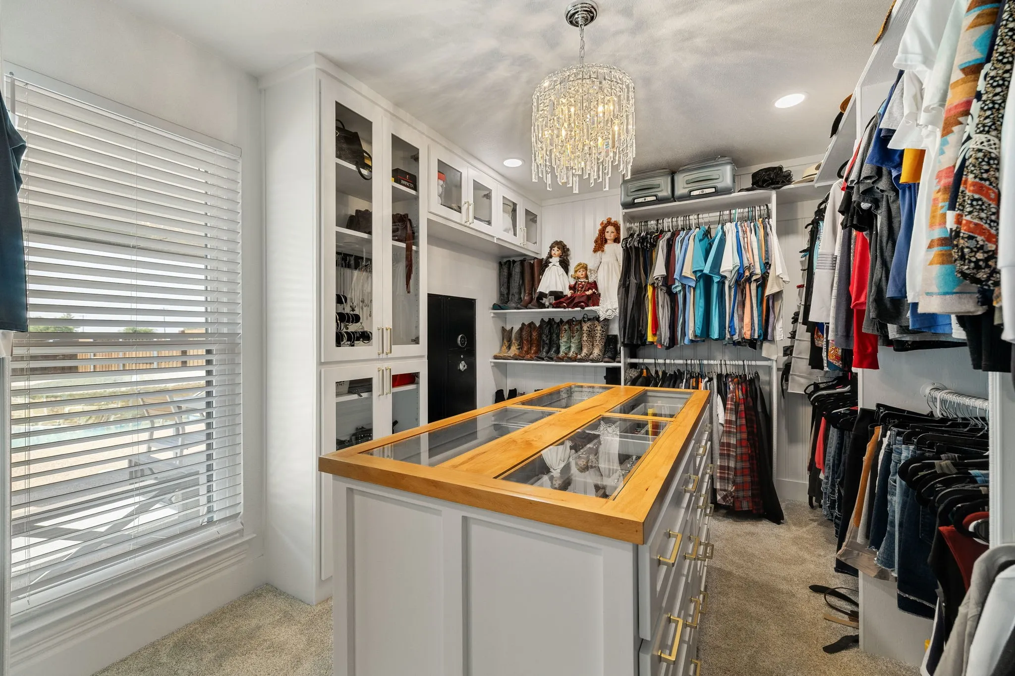 Custom closet system featuring a central island with a wood-finish top and glass inserts, multiple hanging rods, and built-in shelving