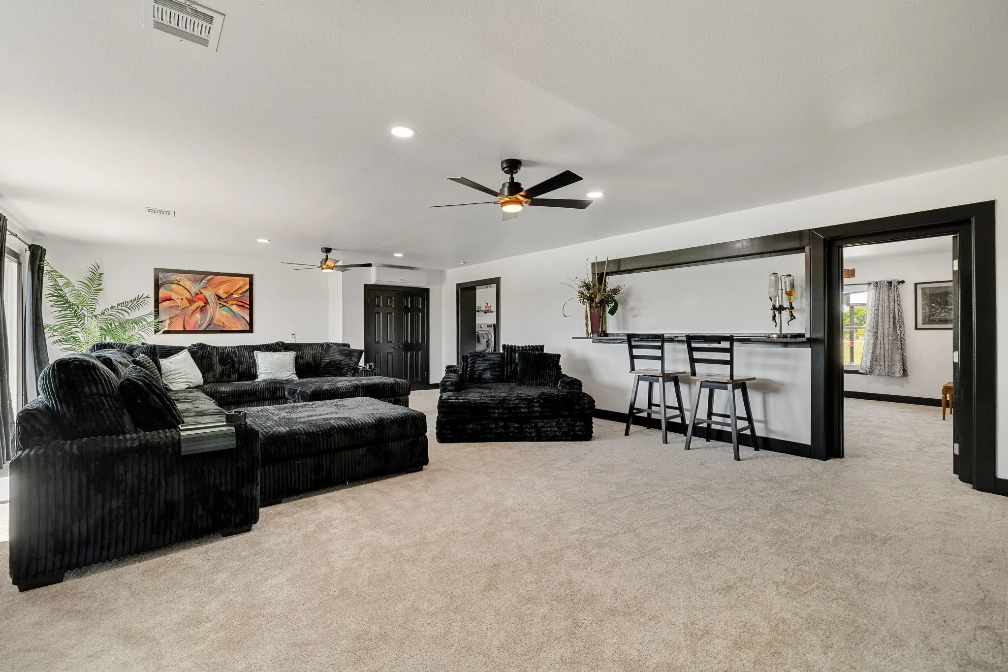 Spacious room with light-colored carpeting, recessed lighting, and two ceiling fans