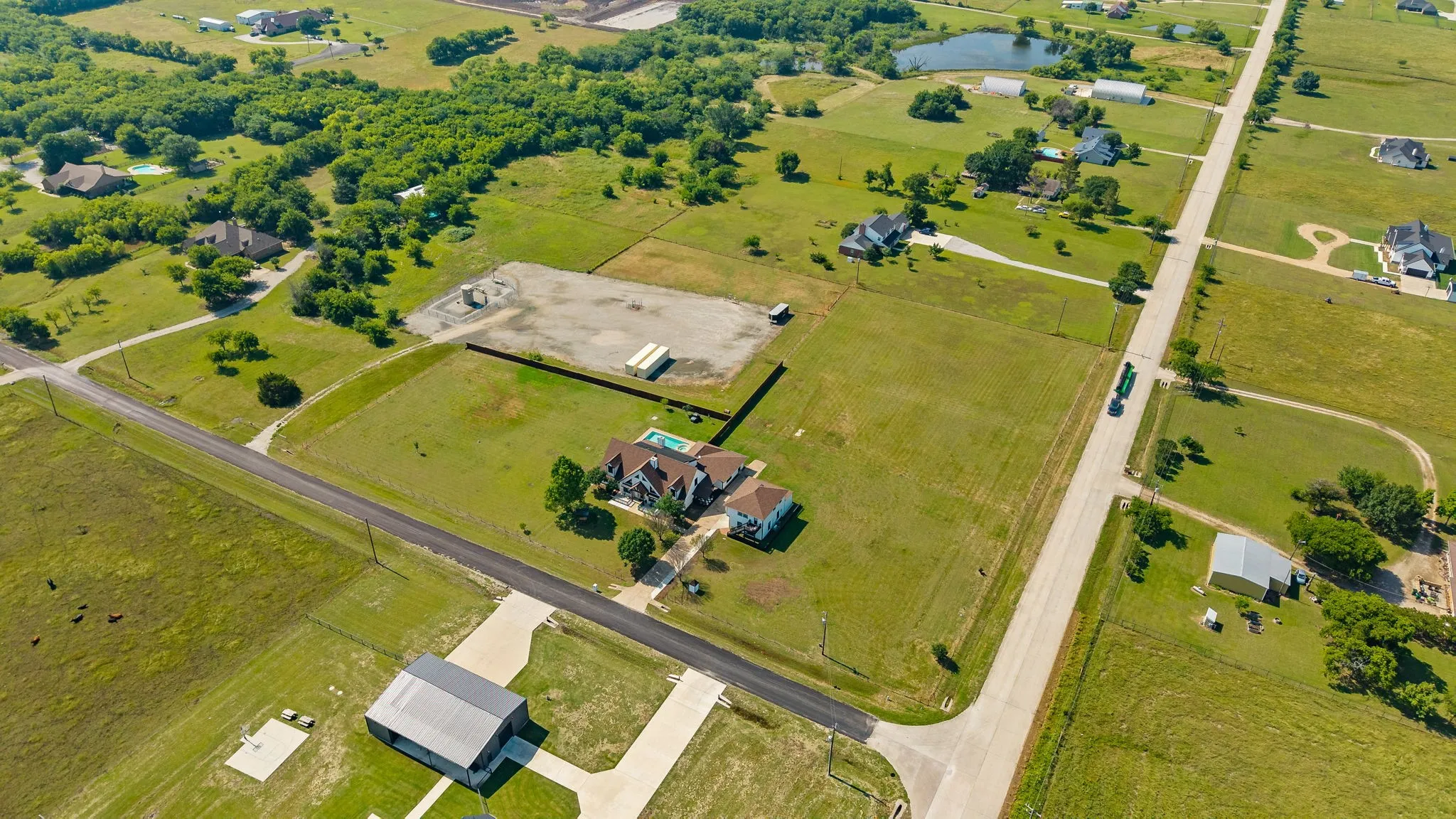 Expansive rural property featuring a large residence with a swimming pool, multiple outbuildings, and an extensive land area with mature trees and open fields