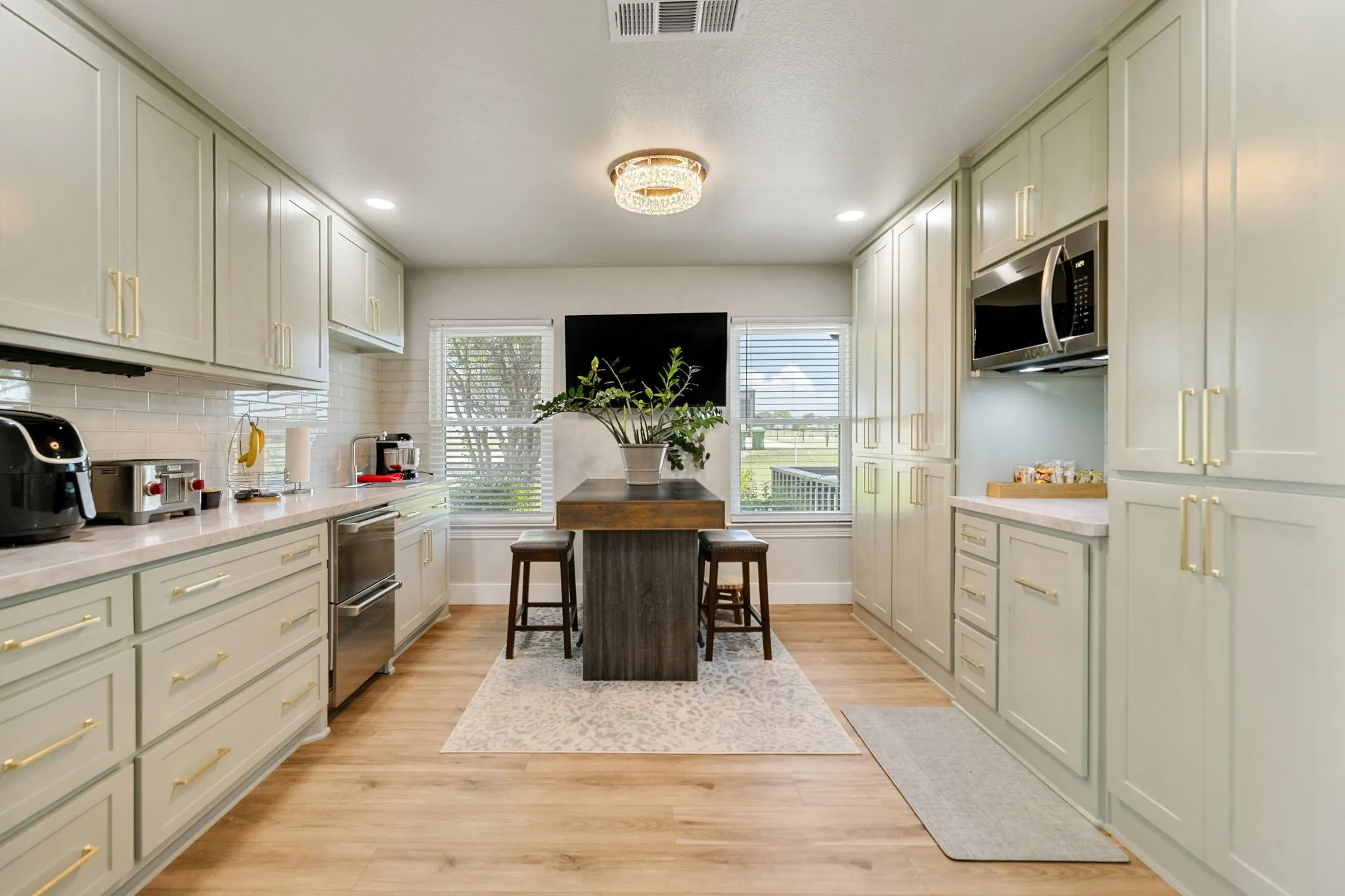 Light-toned cabinetry with gold-toned hardware, stone-finish countertops, wood-finish flooring, and recessed lighting
