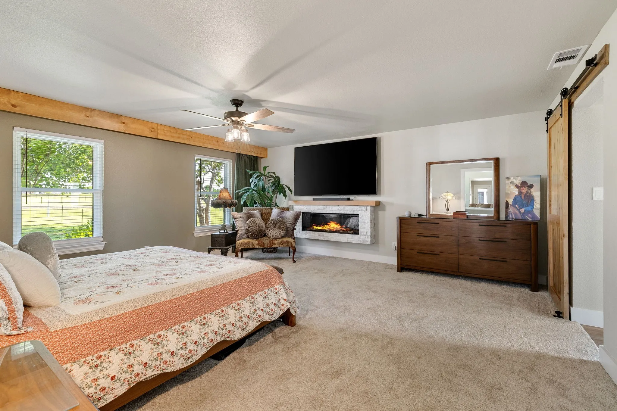 Spacious room featuring light carpet flooring, a ceiling fan, and a wood-beam accent