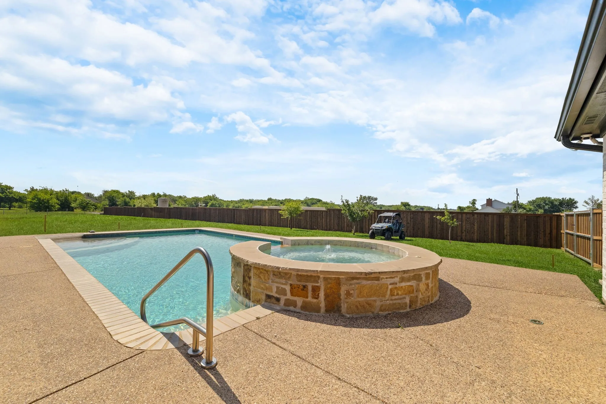 Outdoor pool and accompanying spa with stone surround