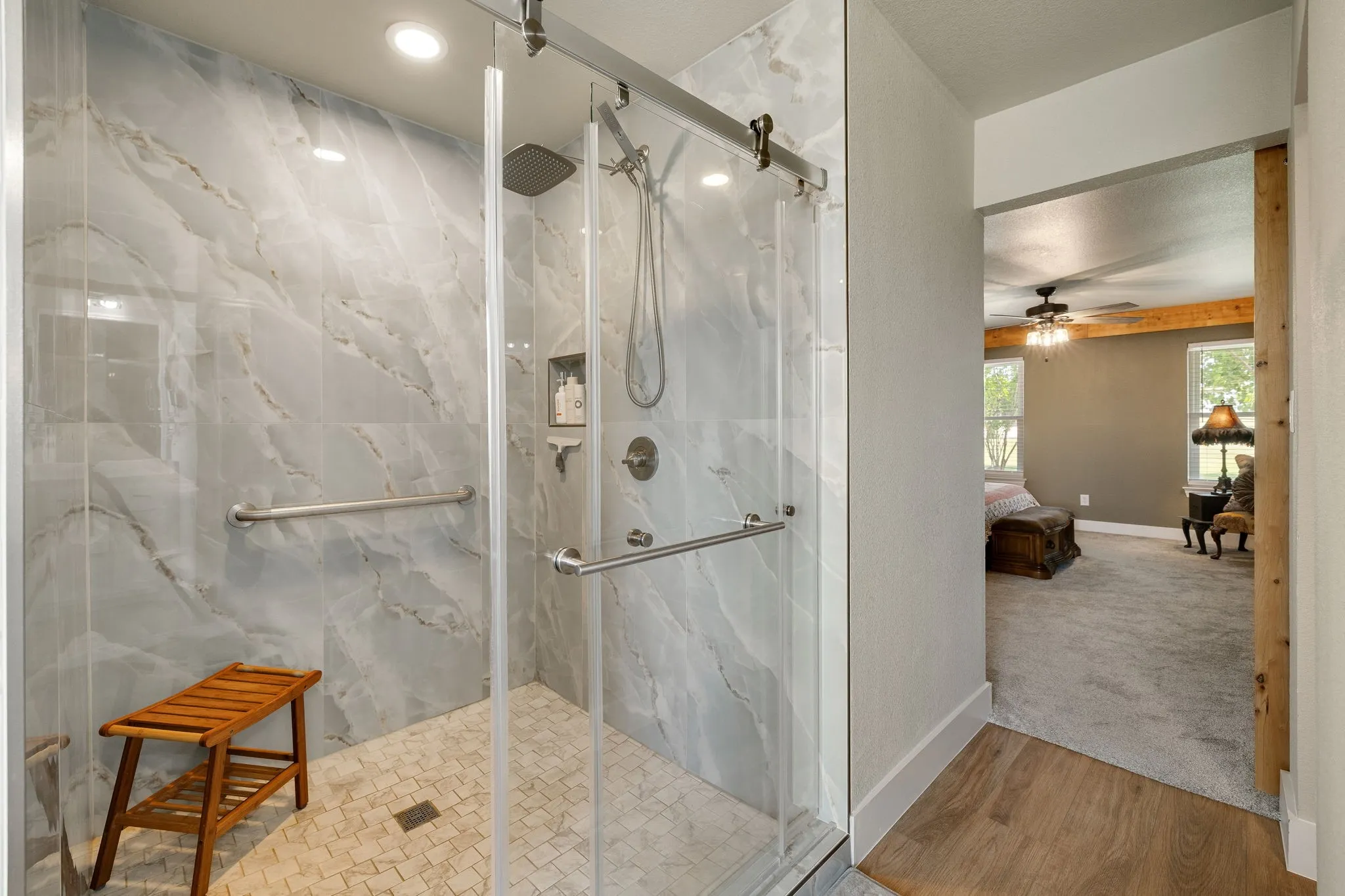 Walk-in shower featuring large-format marble-look wall tiles, a rain shower head, and a hand-held shower fixture