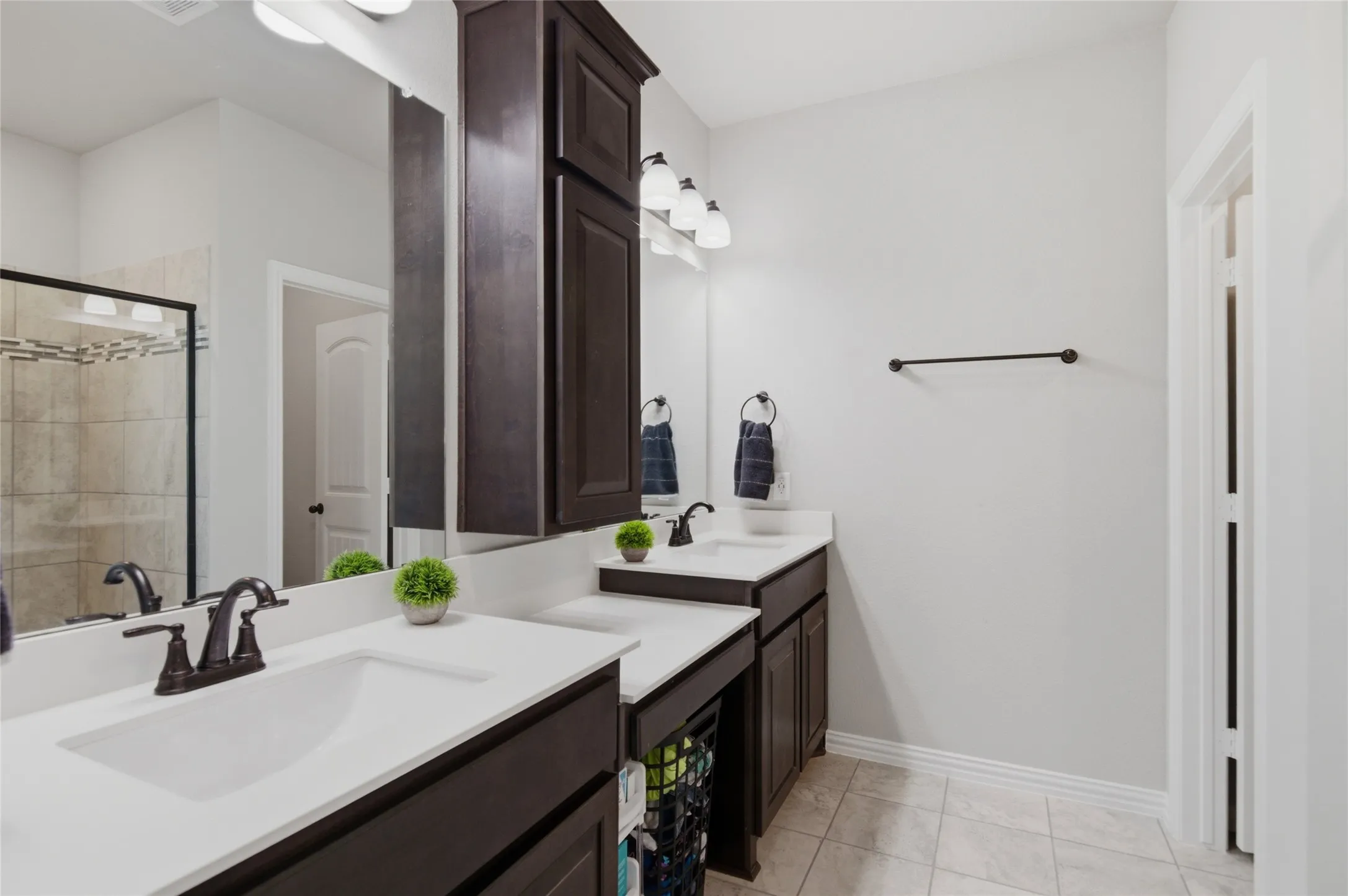 His and her vanities with extra storage cabinet. Larger shower option was built in this home.