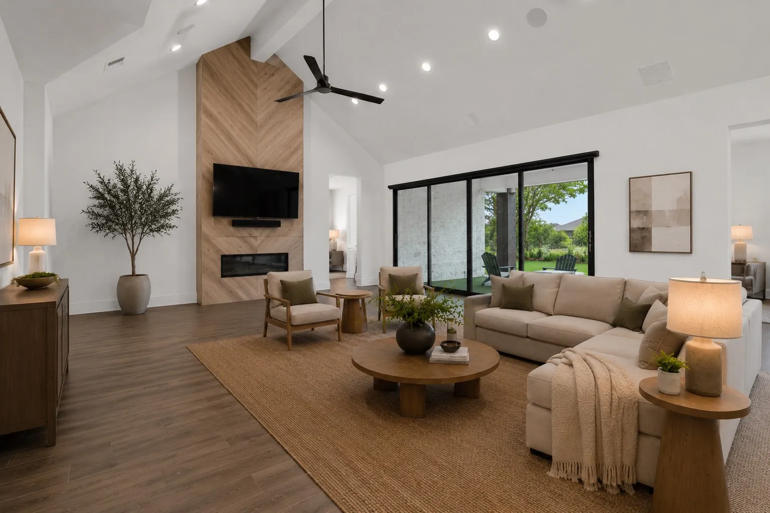 A show-stopping open-concept great room where soaring ceilings, rich wood-look flooring, and a sleek designer kitchen flow effortlessly into the backyard through dramatic sliding glass doors. Built for everyday living and unforgettable entertaining. (Ai Staged)