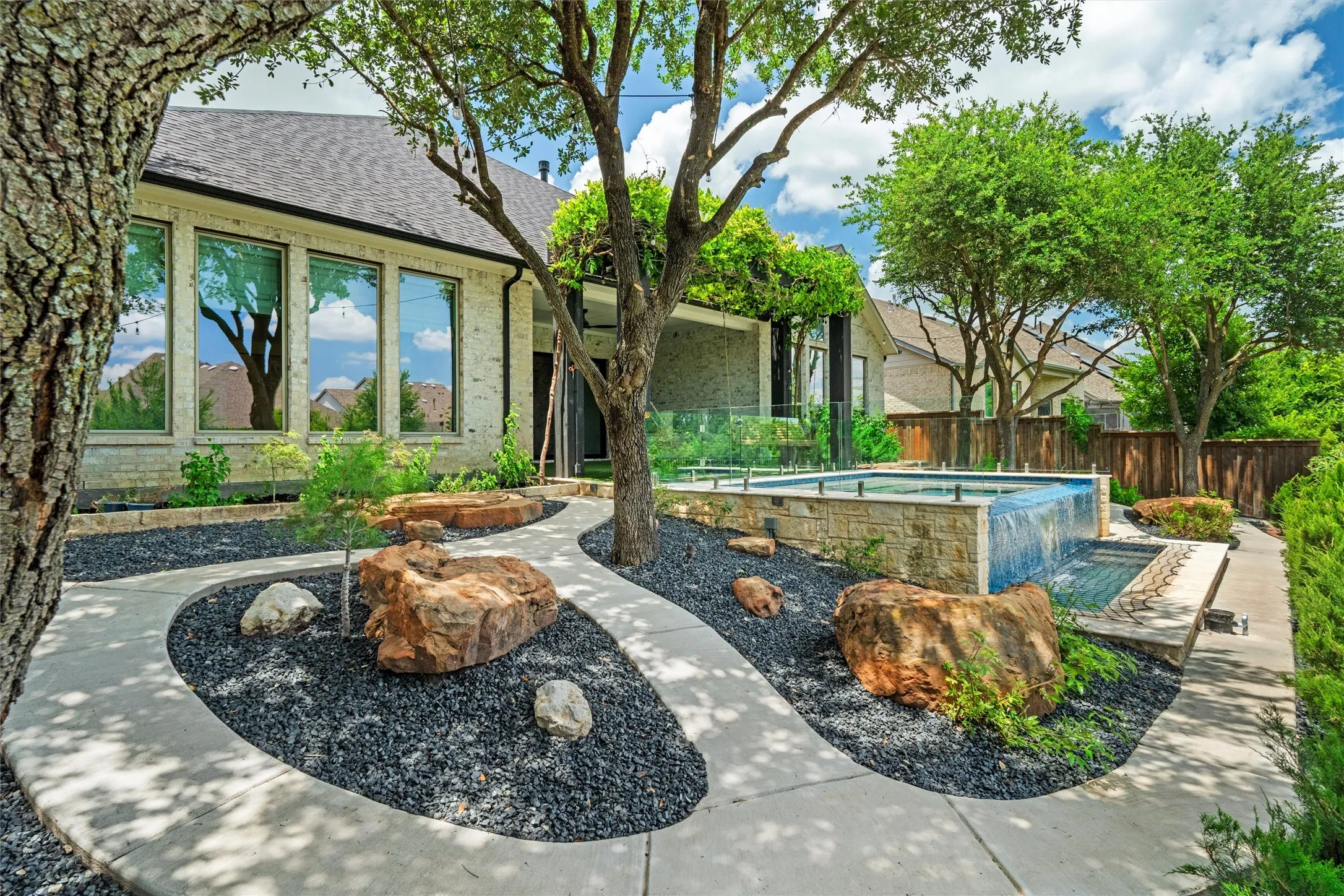This breathtaking backyard combines lush landscaping, dramatic boulders, mature trees, a cascading pool waterfall, and multiple outdoor gathering spaces. It is a true private oasis designed for relaxing weekends and unforgettable entertaining.