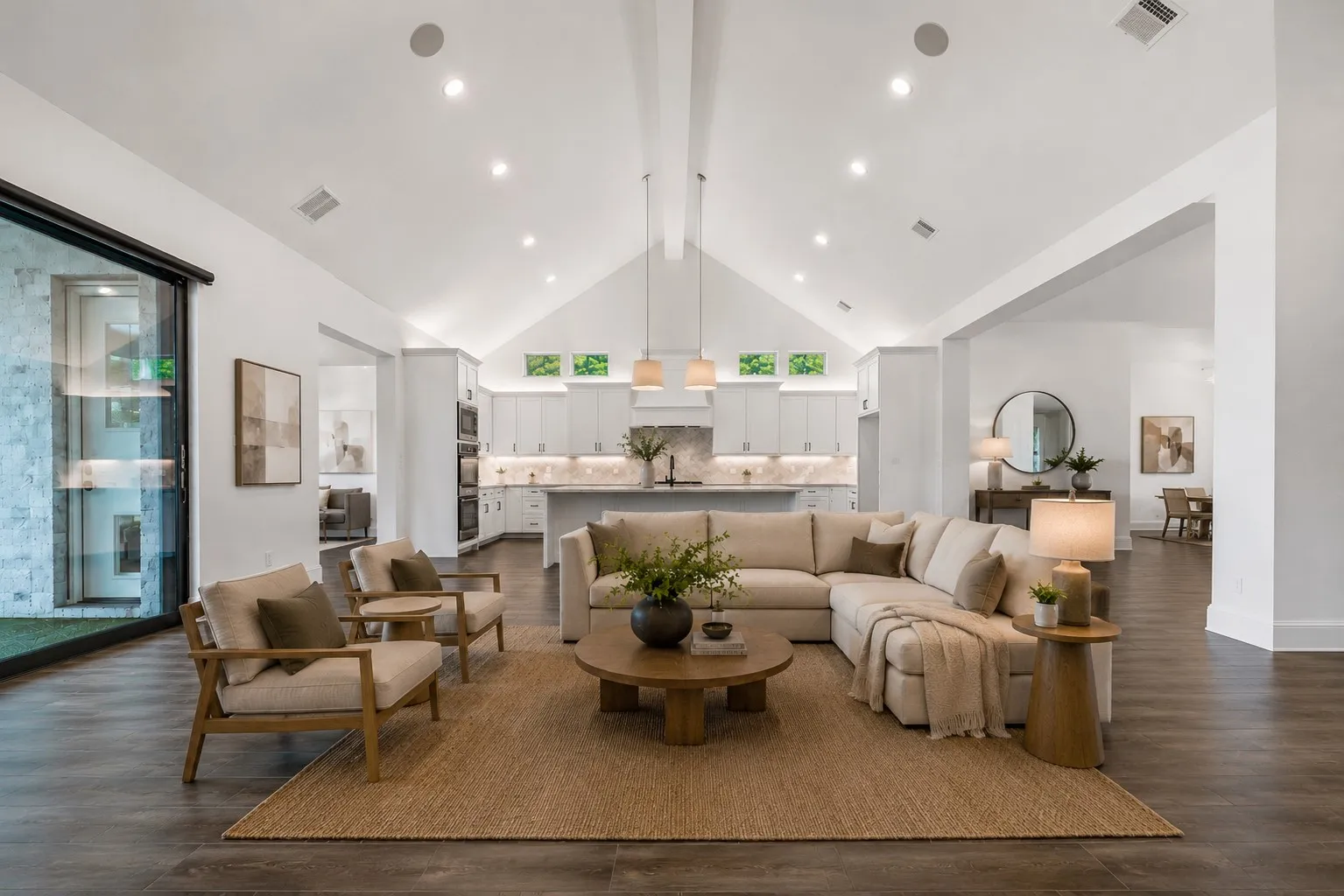 This expansive main living space delivers instant wow factor with a vaulted ceiling, statement lighting, clean architectural lines, and a chef-inspired kitchen that anchors the heart of the home. (Ai Staged)