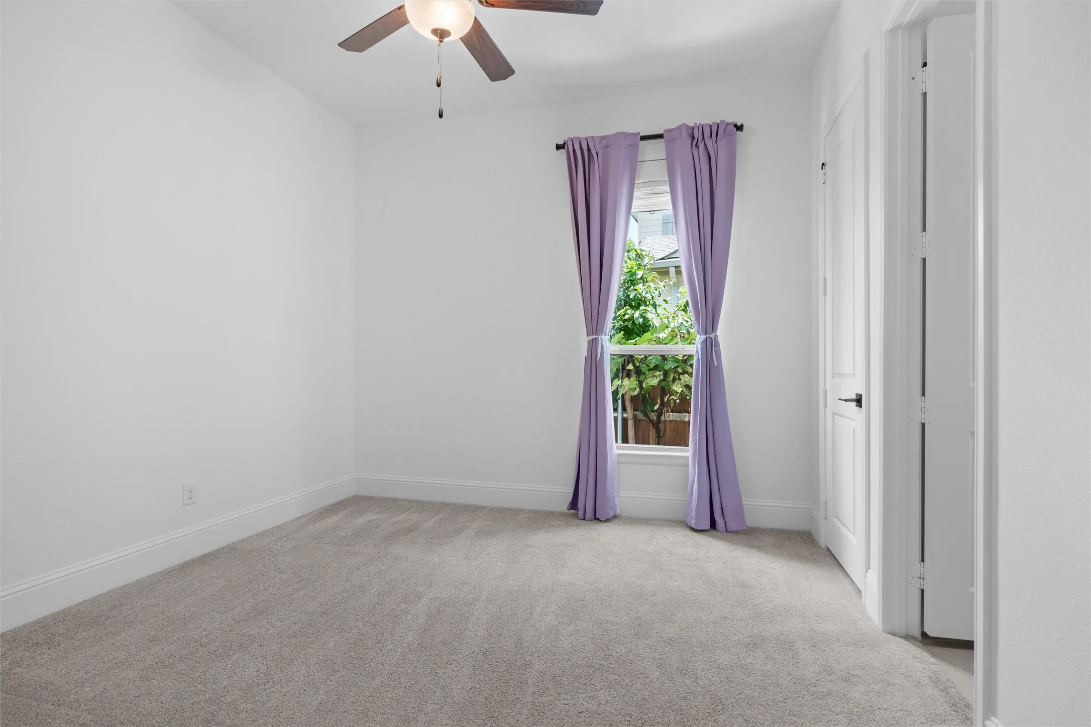 Comfortable and versatile, this spacious bedroom features plush carpet, a ceiling fan, and a sunny window—an easy fit for guests, kids, or a private work-from-home space.