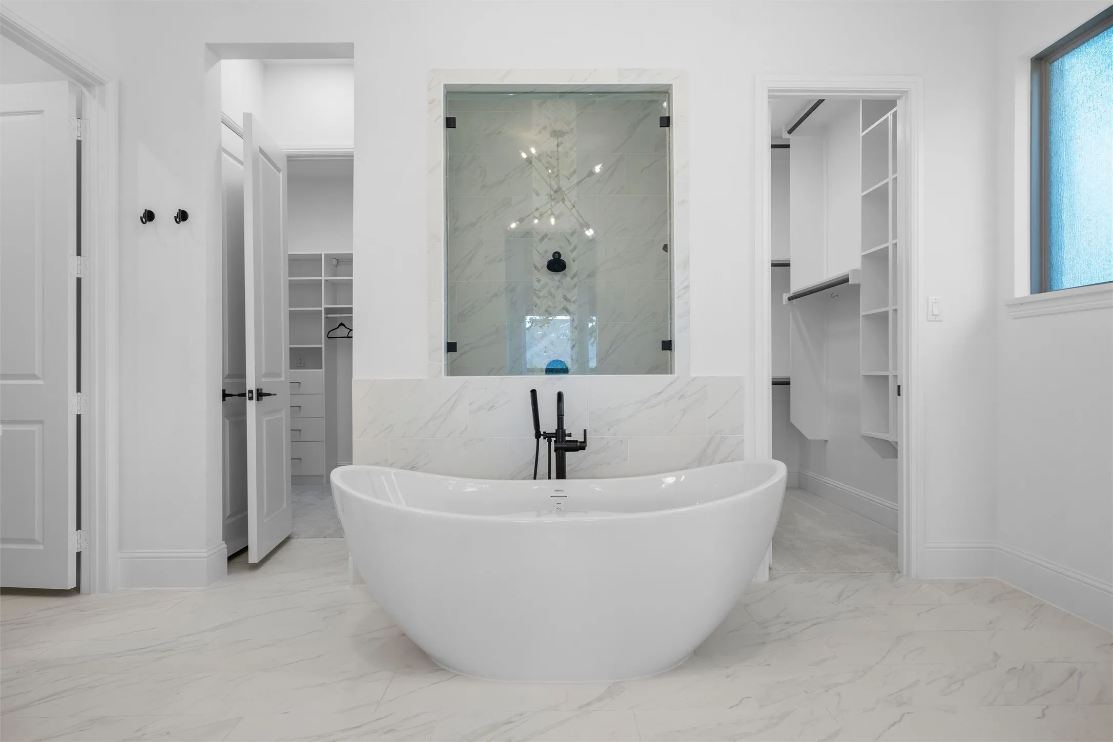 Designed to feel like a private spa, this elegant bath centers around a dramatic soaking tub framed by a glass-enclosed shower, generous storage, and dual walk-in closet access.