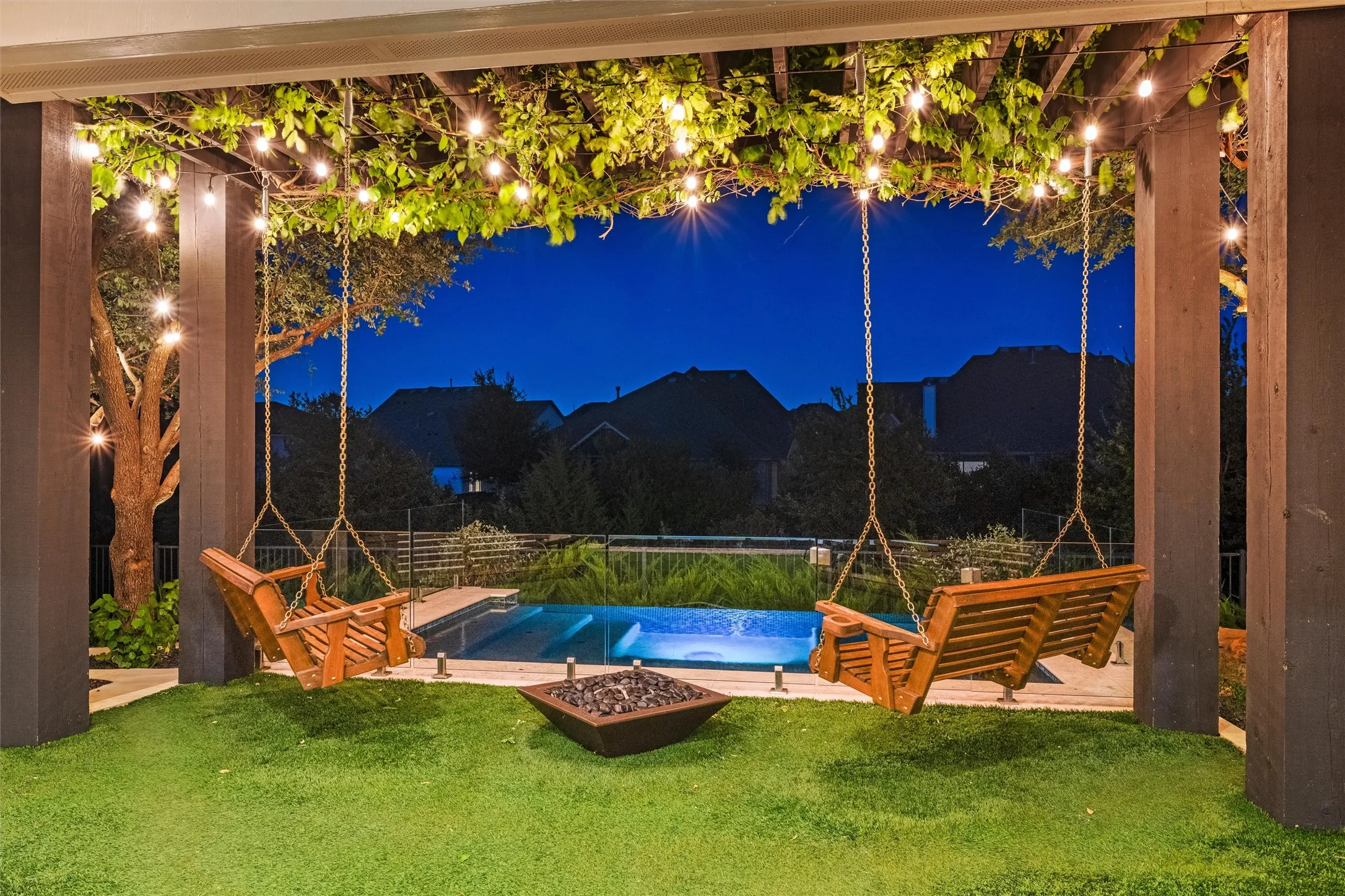An unforgettable evening retreat where vine-covered beams, glowing café lights, twin swings, and a fire feature set the scene for poolside nights that feel straight out of a luxury resort.