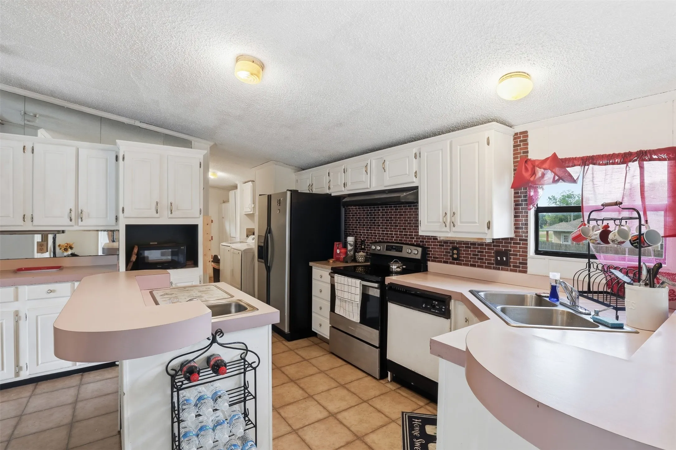View of kitchen from mirrored wall. Kitchen island with a sink. Also looks into the laundry room.