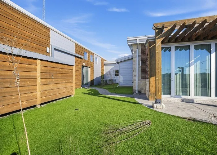 Manicured artificial turf lawn, privacy fencing, wood pergola, and sliding glass patio doors
