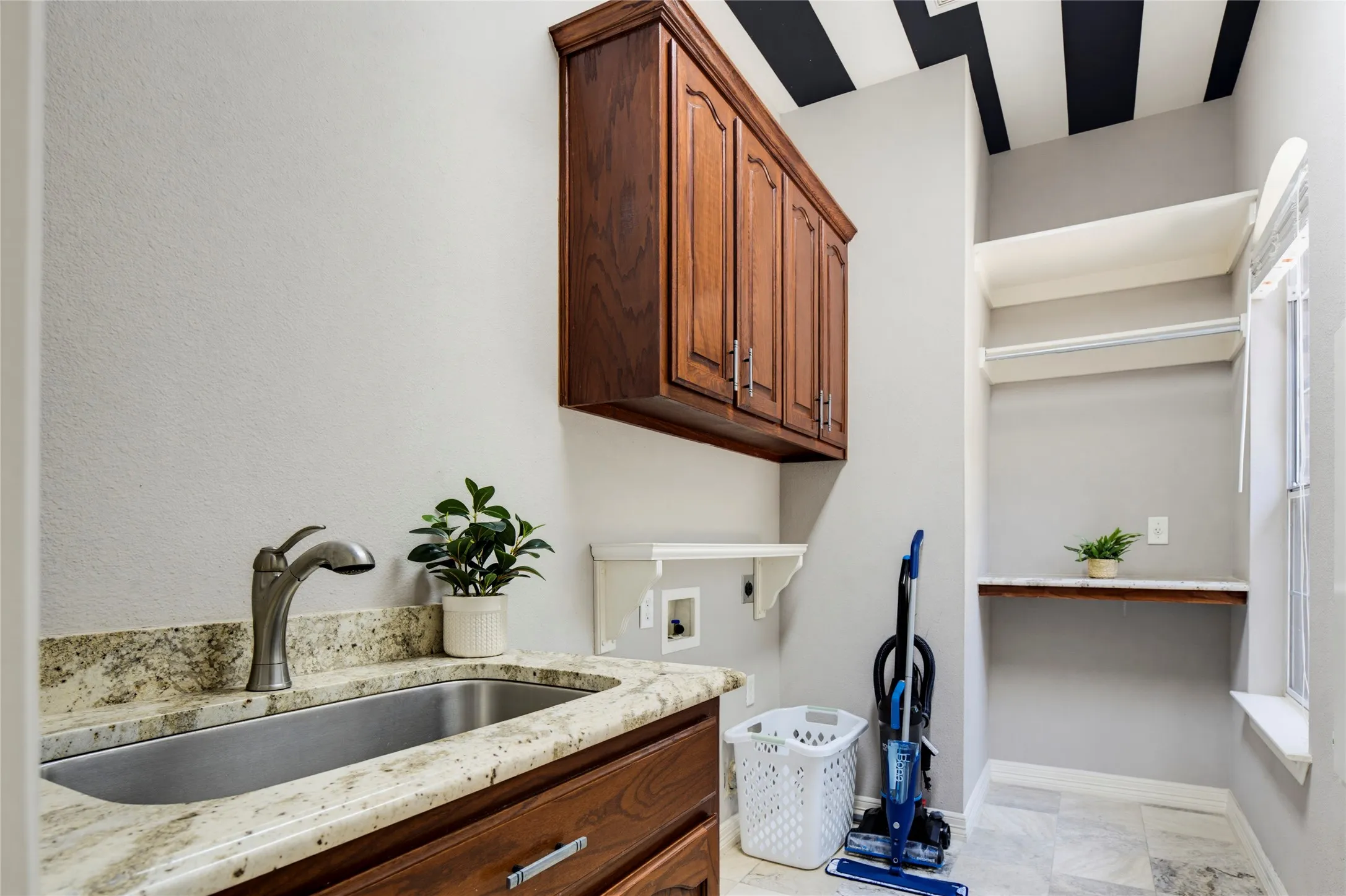 Laundry room is located just off of the kitchen by the garage. Great cabinet space plus a sink, folding counter, and hanging space.
