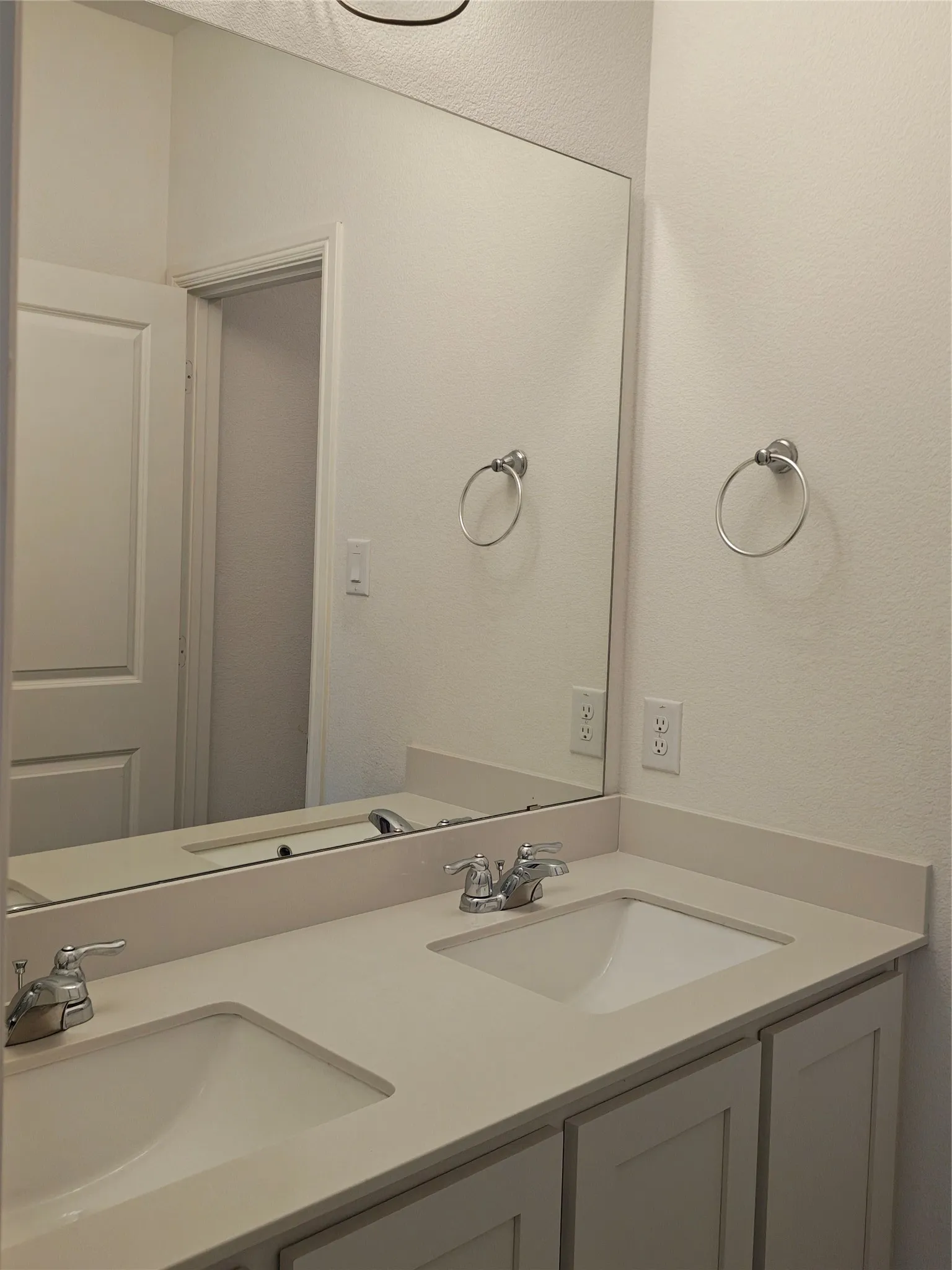Dual undermount sinks, chrome faucets, and a full-width vanity mirror