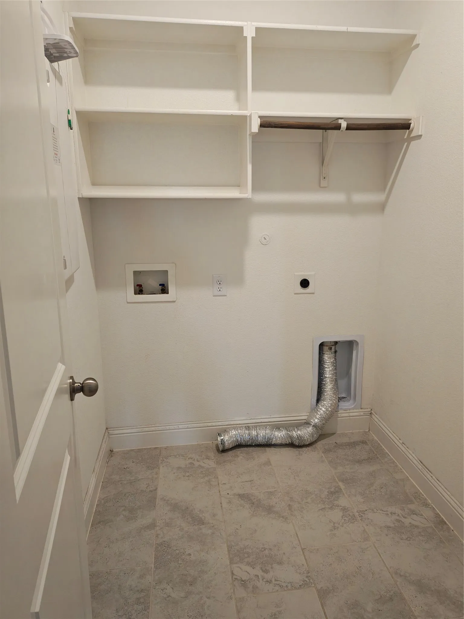 Utility area featuring built-in shelving, a clothes hanging rod, and tile flooring