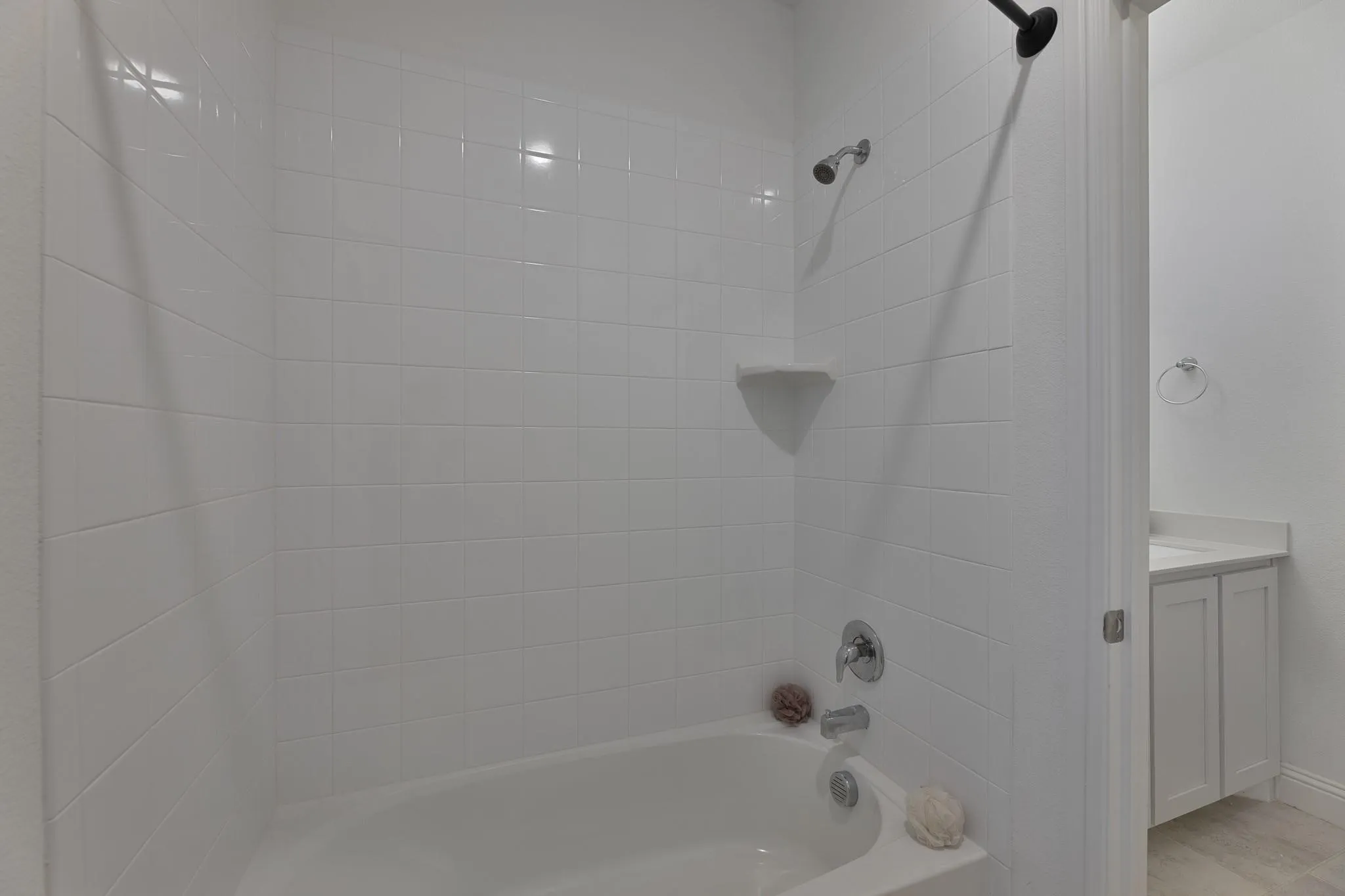 White subway tile shower surround with an integrated corner shelf and a chrome shower fixture