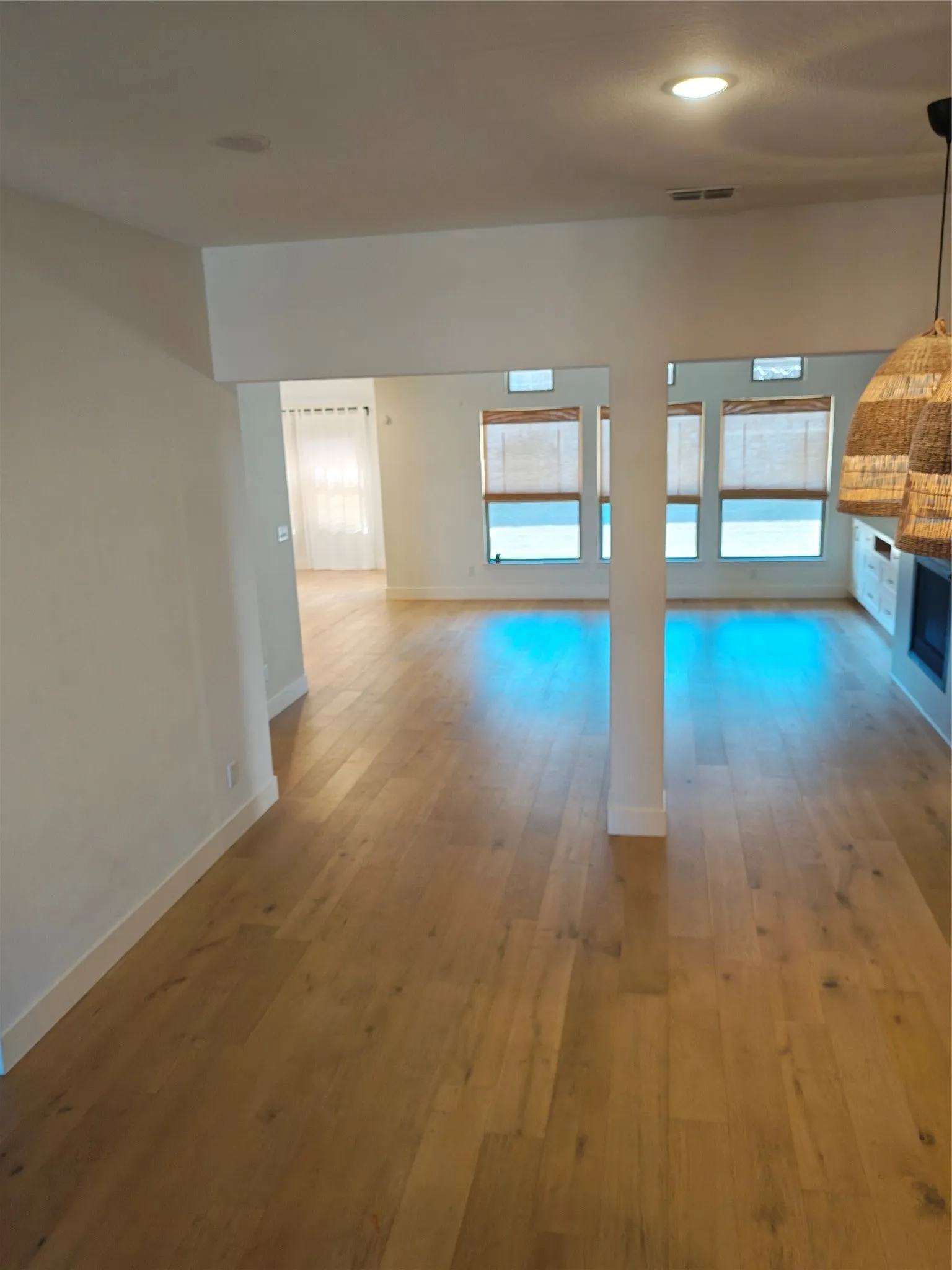 Hardwood-finish flooring throughout, recessed ceiling lighting, and multiple windows with natural woven blinds