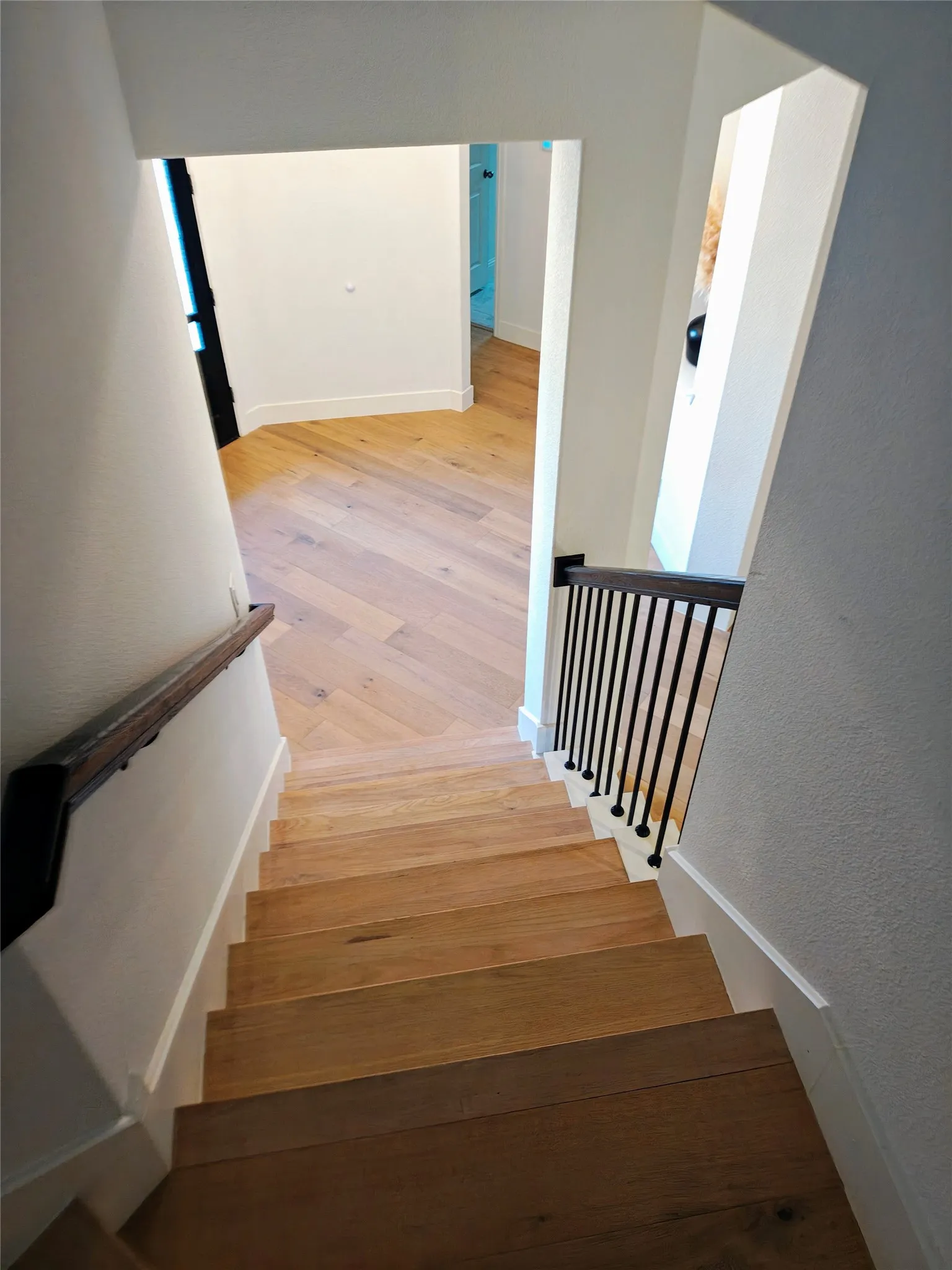 Hardwood staircase with a dark wood-finish handrail and black metal balusters